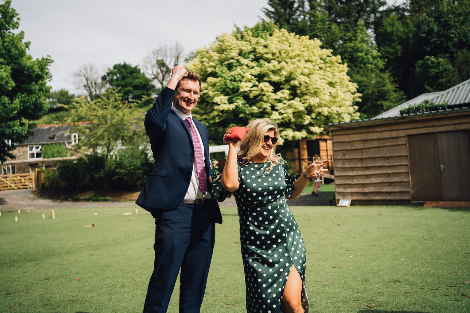Wedding guests mingle on a lush green lawn during an outdoor summer celebration.