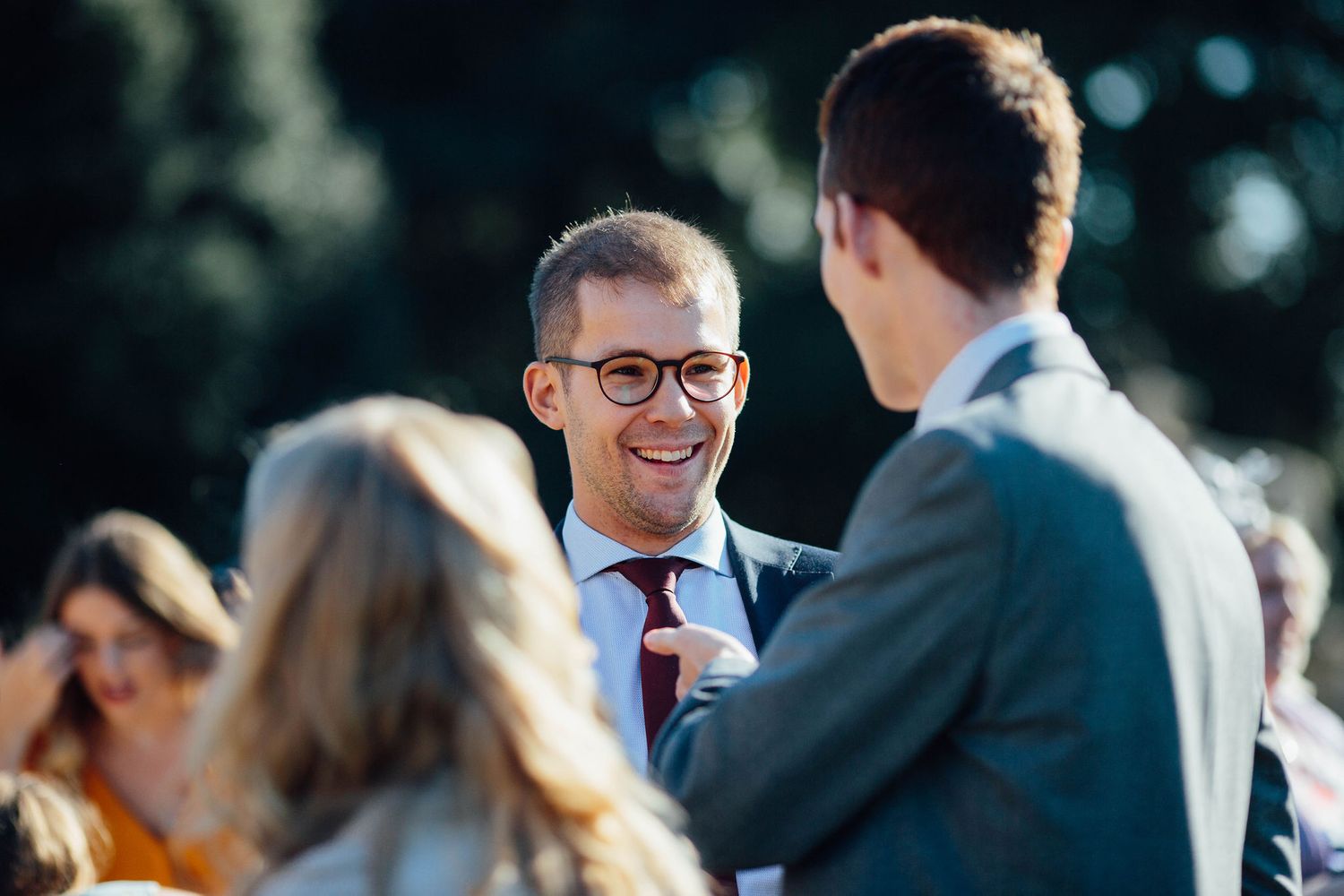 Guests engage in lively conversation during an outdoor wedding celebration.