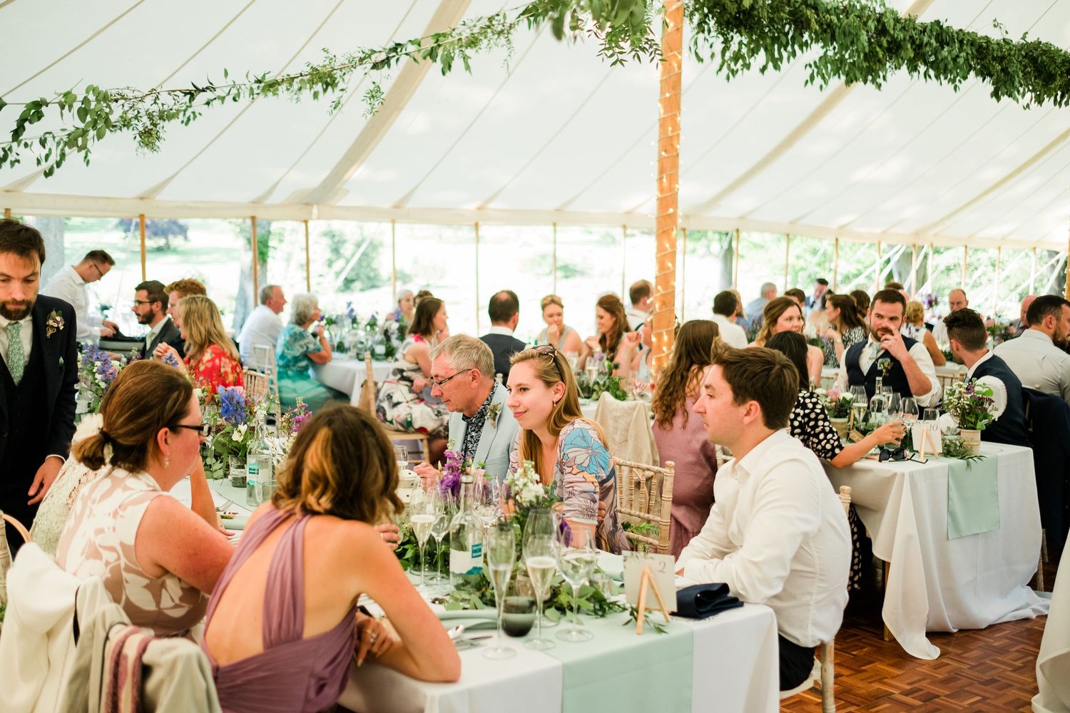 Large wedding reception tent filled with guests seated at decorated tables.