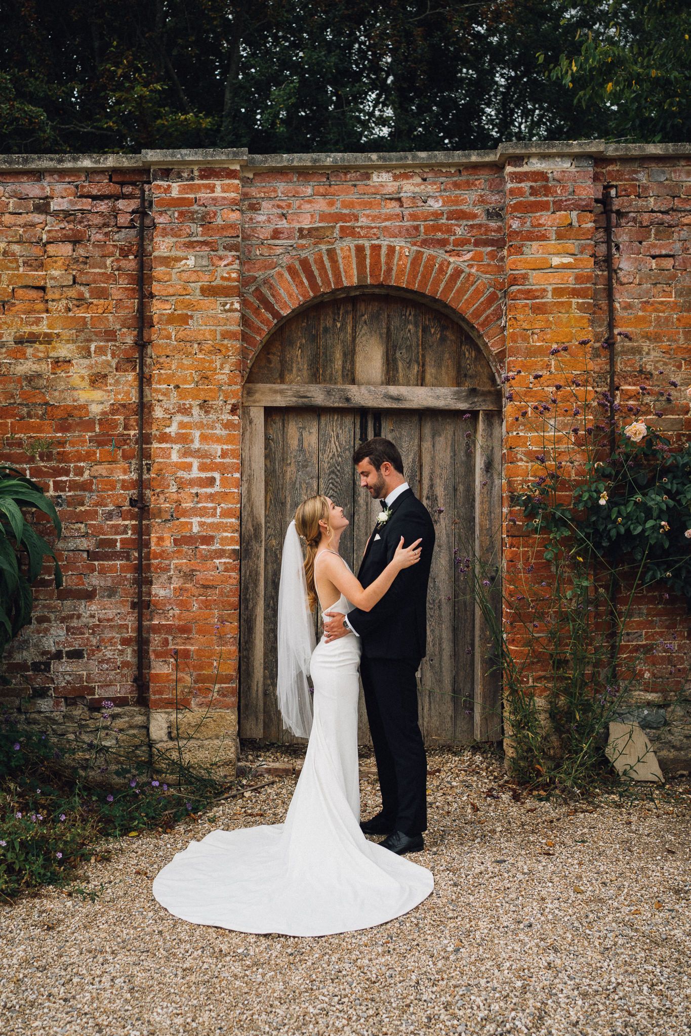A romantic wedding photoshoot sequence against a rustic brick wall with an arched wooden door.