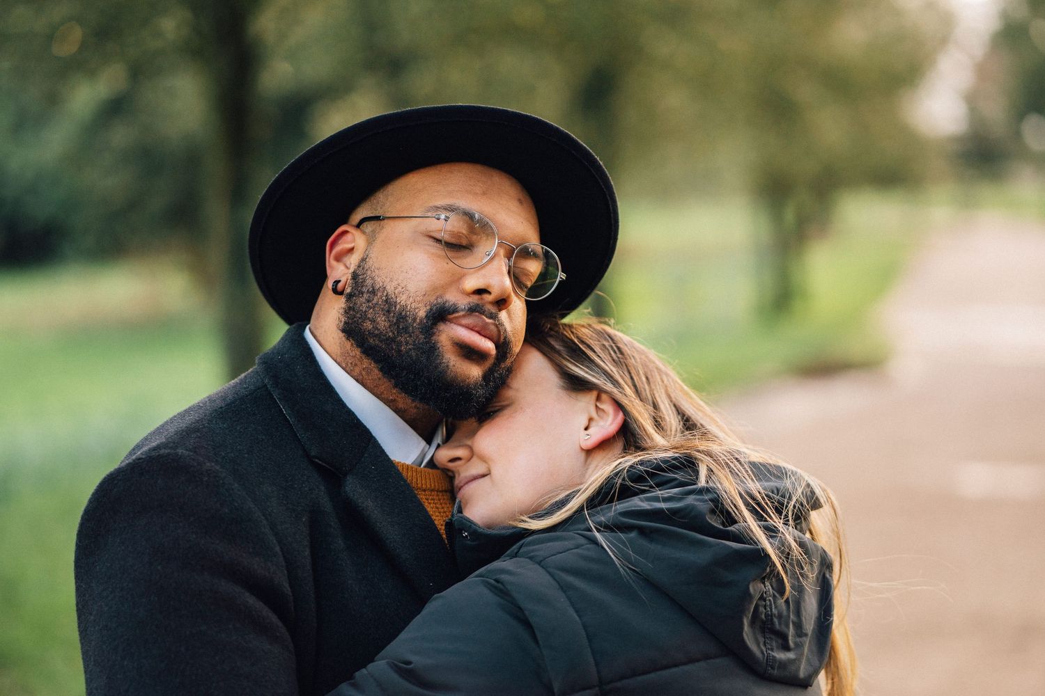 Intimate embrace between two people on a park pathway.
