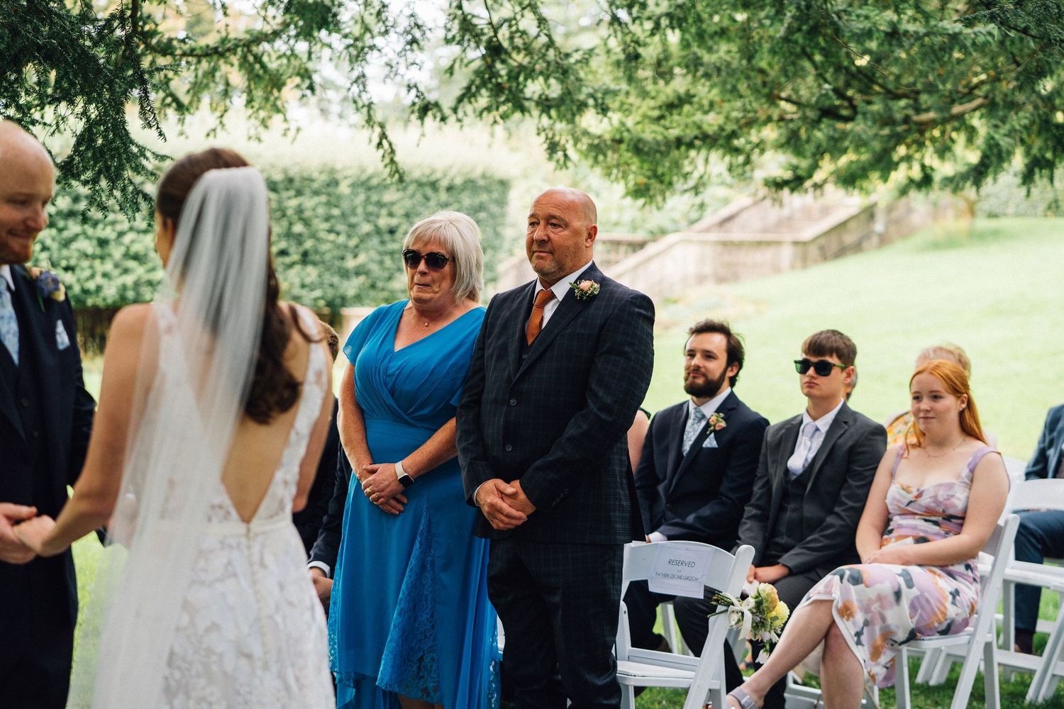 Wedding guests gathered outdoors for ceremony with blue bridesmaid dresses.