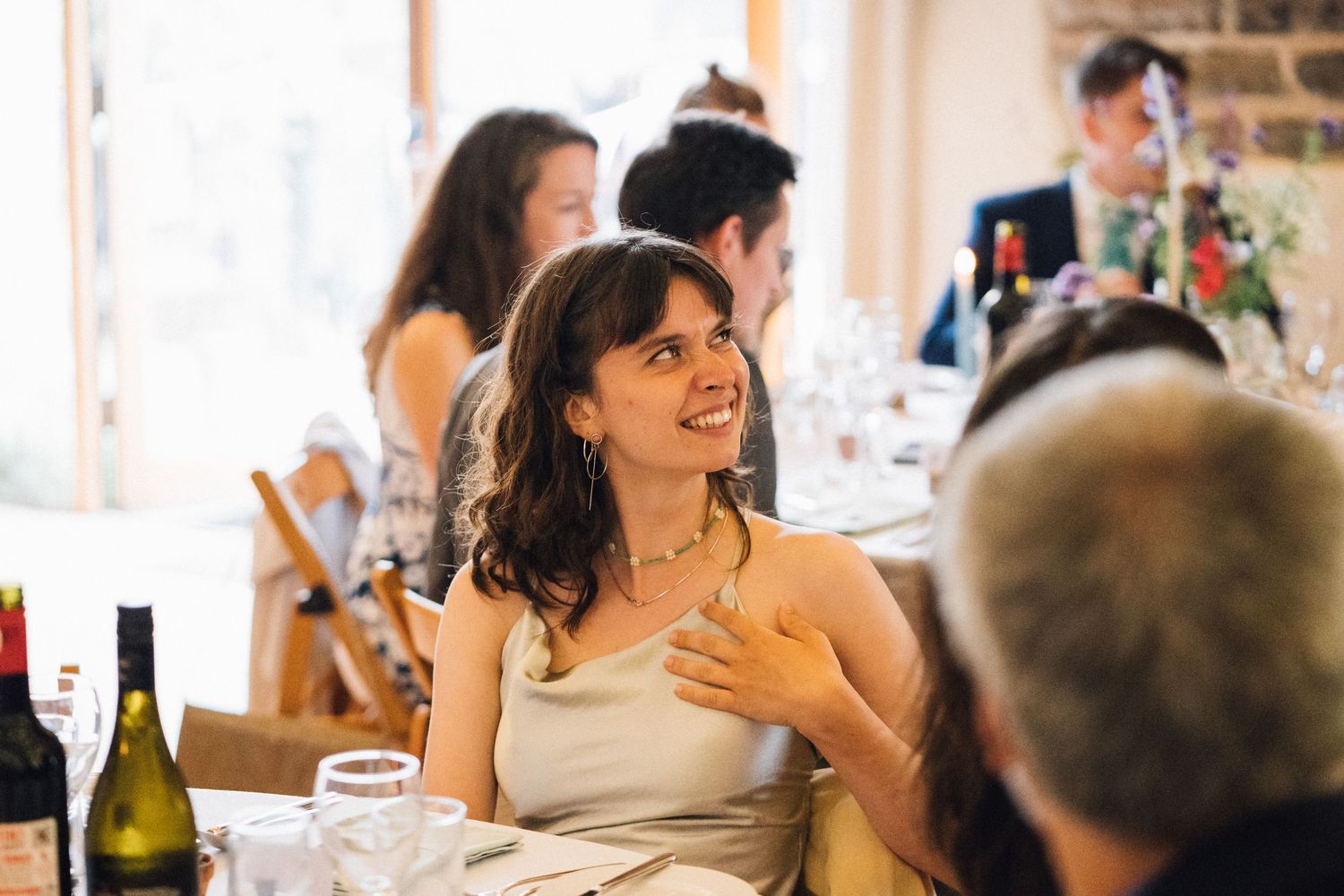 Wedding reception guests enjoying a celebratory meal in a rustic venue with warm lighting.