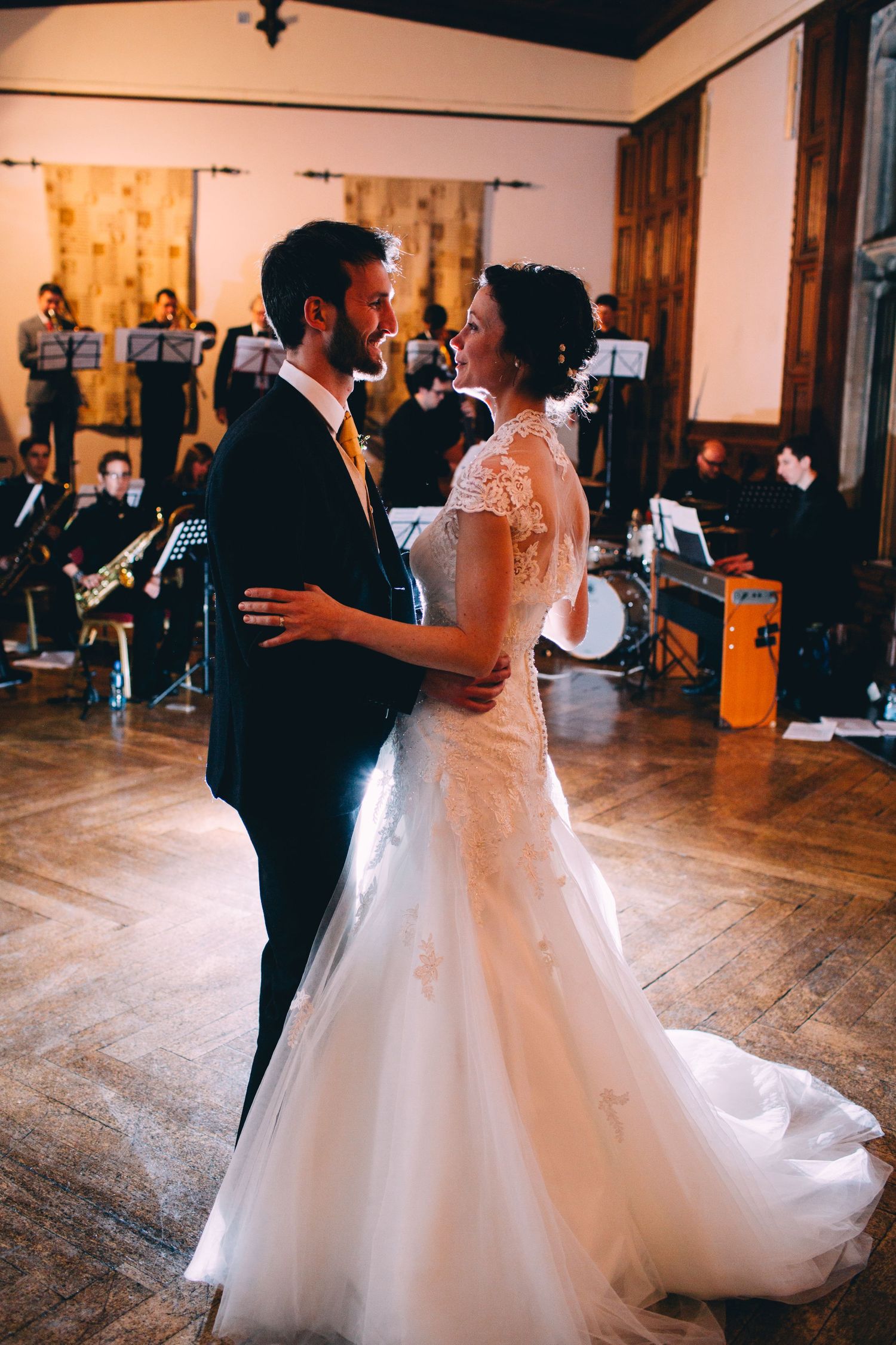 A couple shares their first dance in a reception hall with a live band in the background.