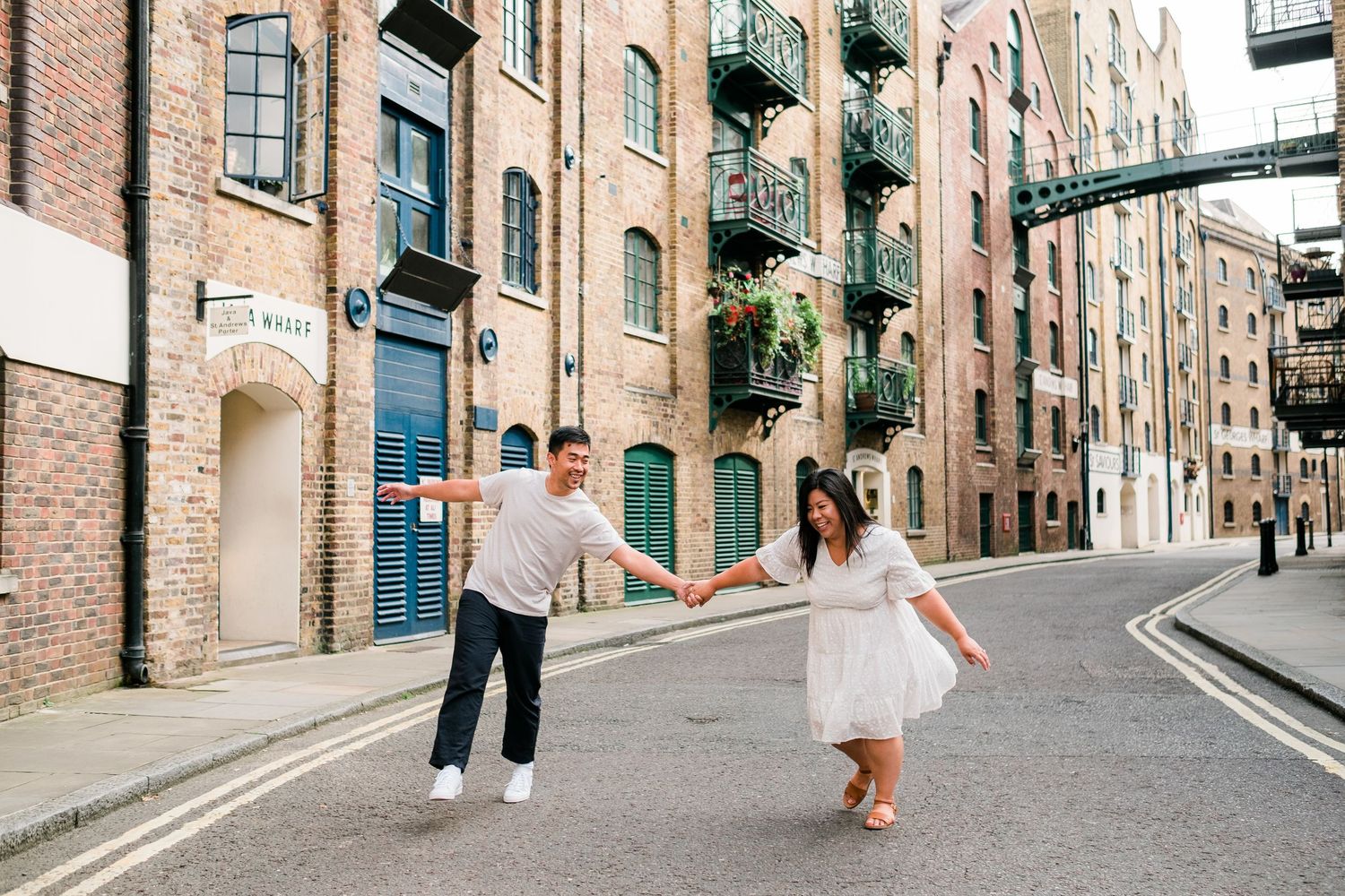 A couple strolls down a charming brick-lined street with historic buildings and cobblestone paths.