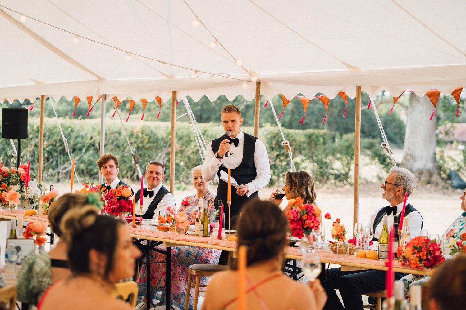 Wedding reception guests dancing and celebrating under an elegant white tent with festive decorations.