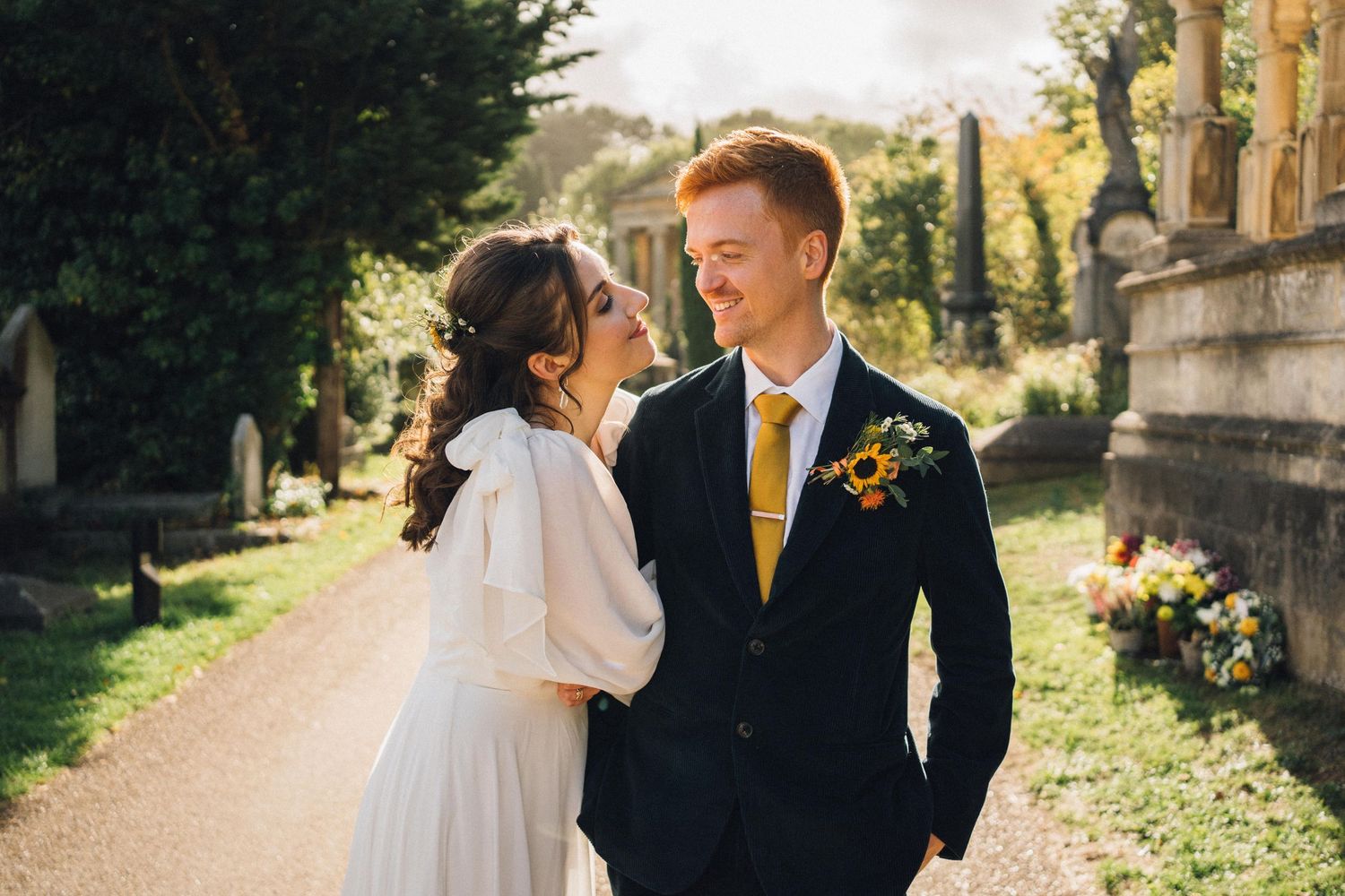 A romantic wedding couple shares tender moments in a sunlit garden setting with yellow floral accents.