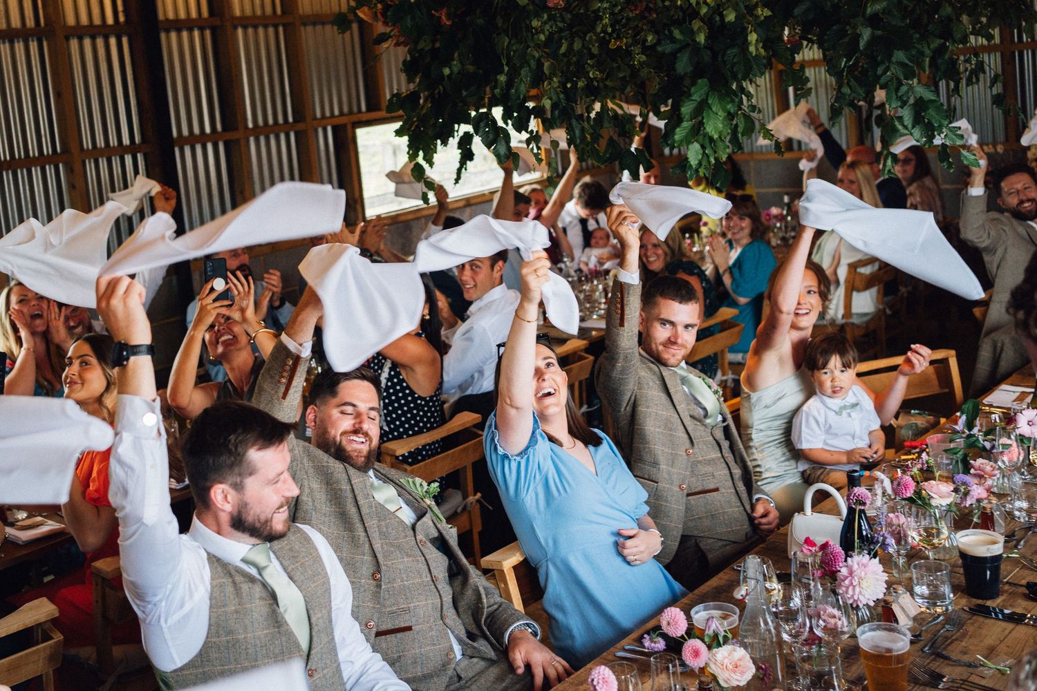 Wedding guests enjoying a celebratory toast during a reception in a rustic indoor venue.