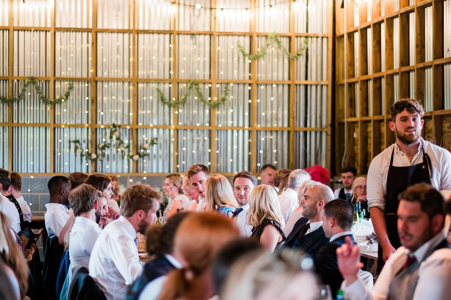 Large crowd gathered inside a wooden-beamed venue space for a wedding celebration.