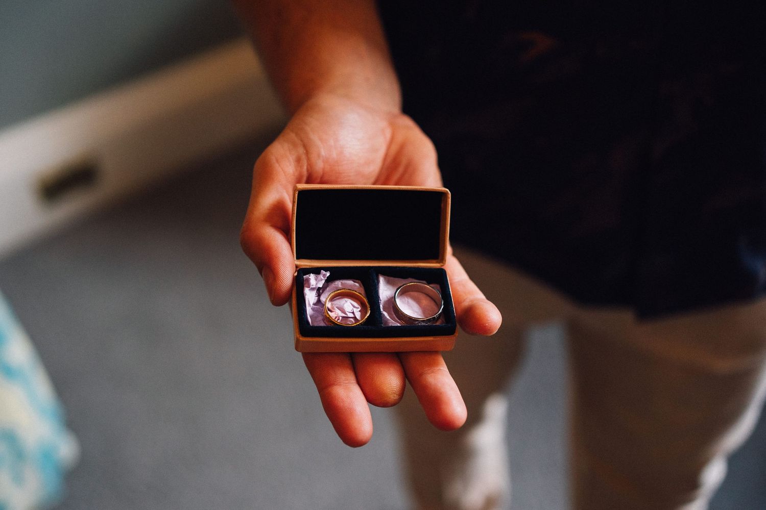 A person holds up a small photo frame or device displaying an image against a blurred background.