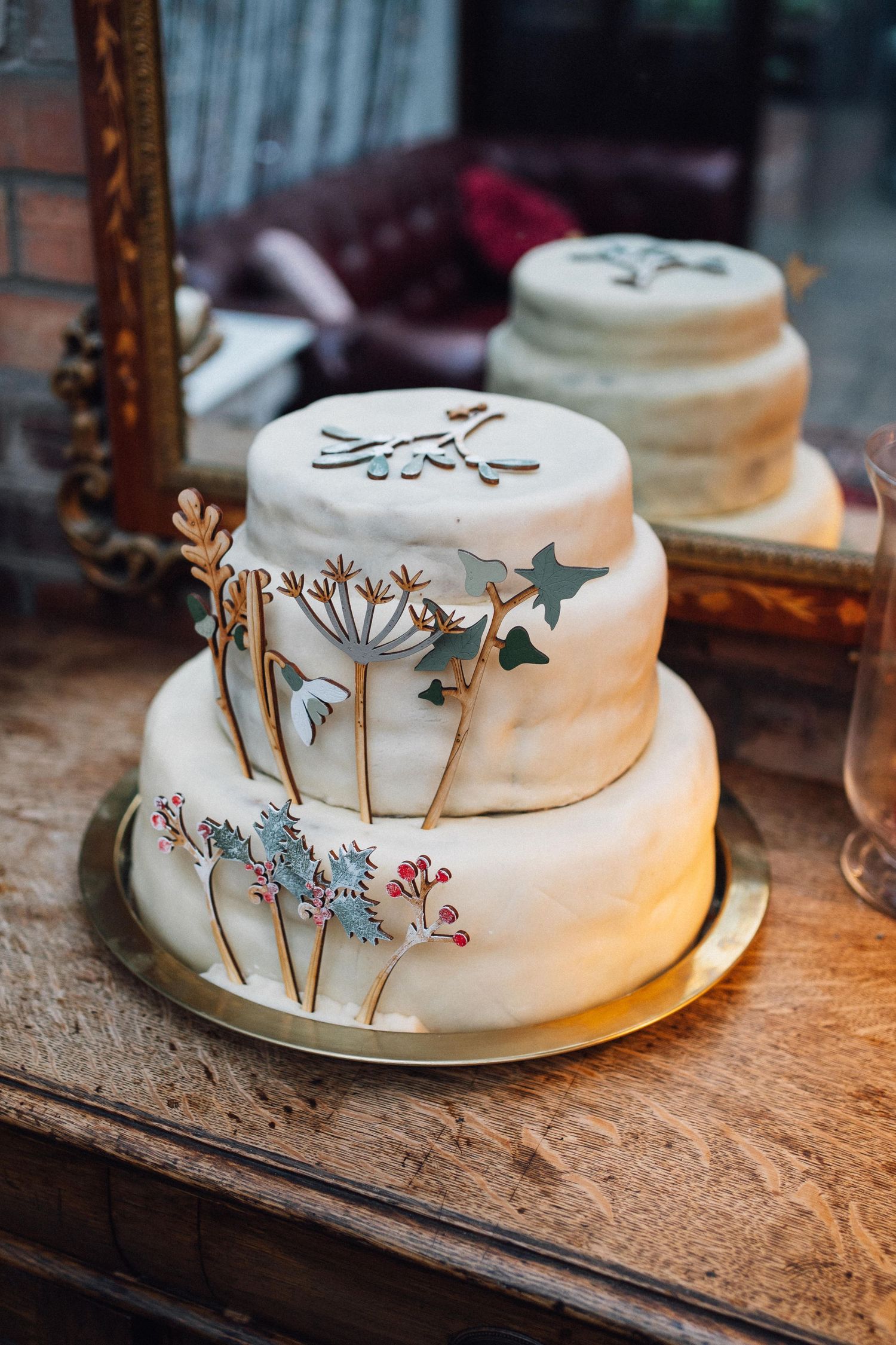 A series of elegant white wedding cakes decorated with delicate floral and botanical designs displayed on rustic wooden surfaces.
