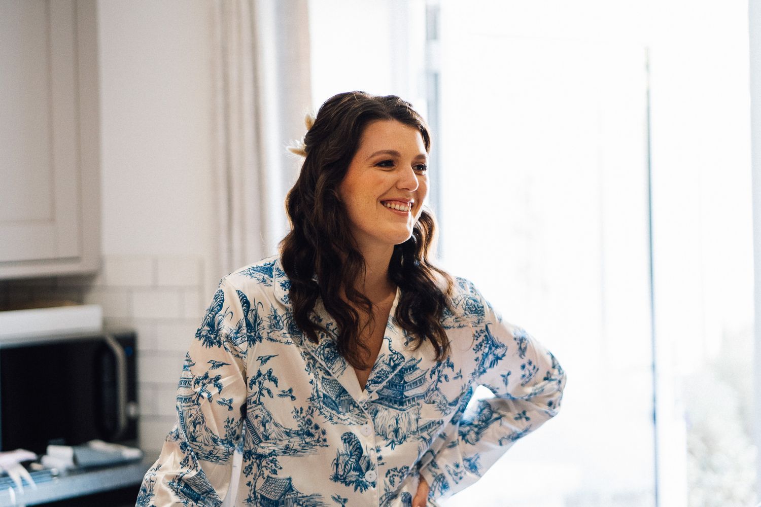 A person wearing a blue and white floral robe lounges on a couch in a bright, modern living room.