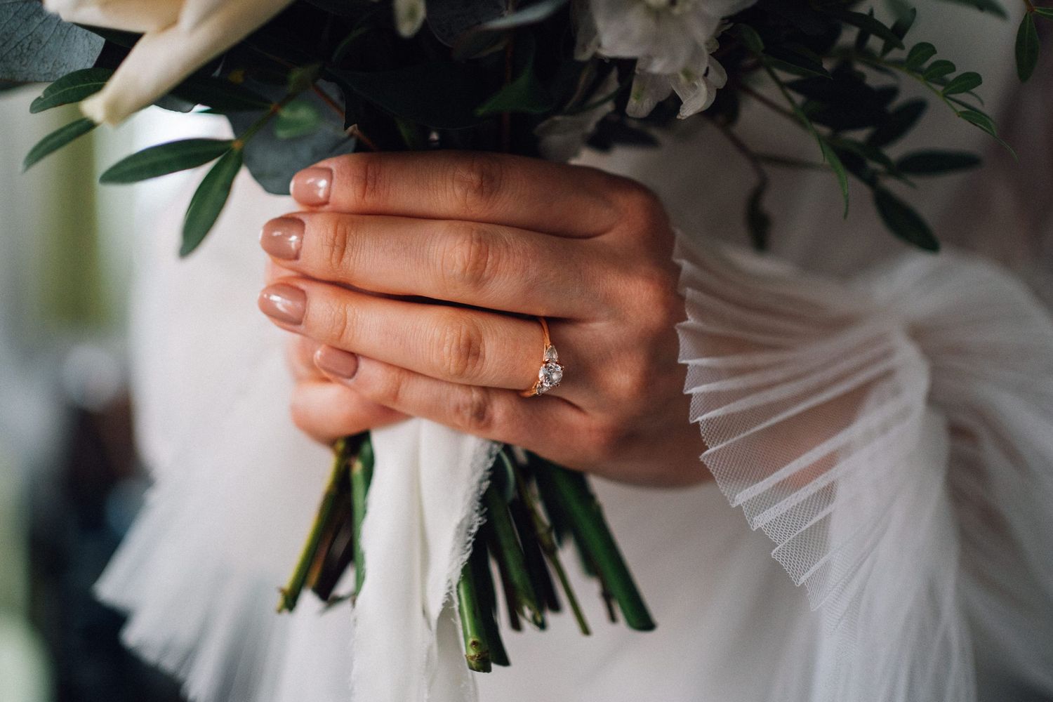 White floral bouquets with greenery being held against formal attire at an elegant event.