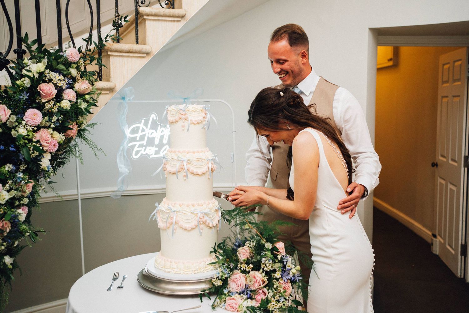 Wedding cake cutting sequence showing white tiered cake decorated with pink floral accents.