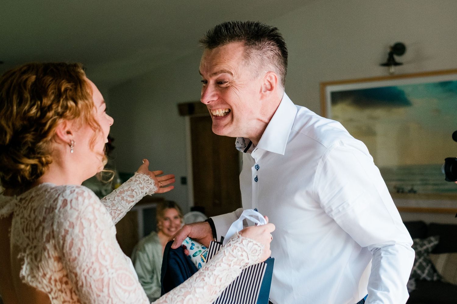 Intimate wedding first look moment showing emotional reactions in an indoor setting.