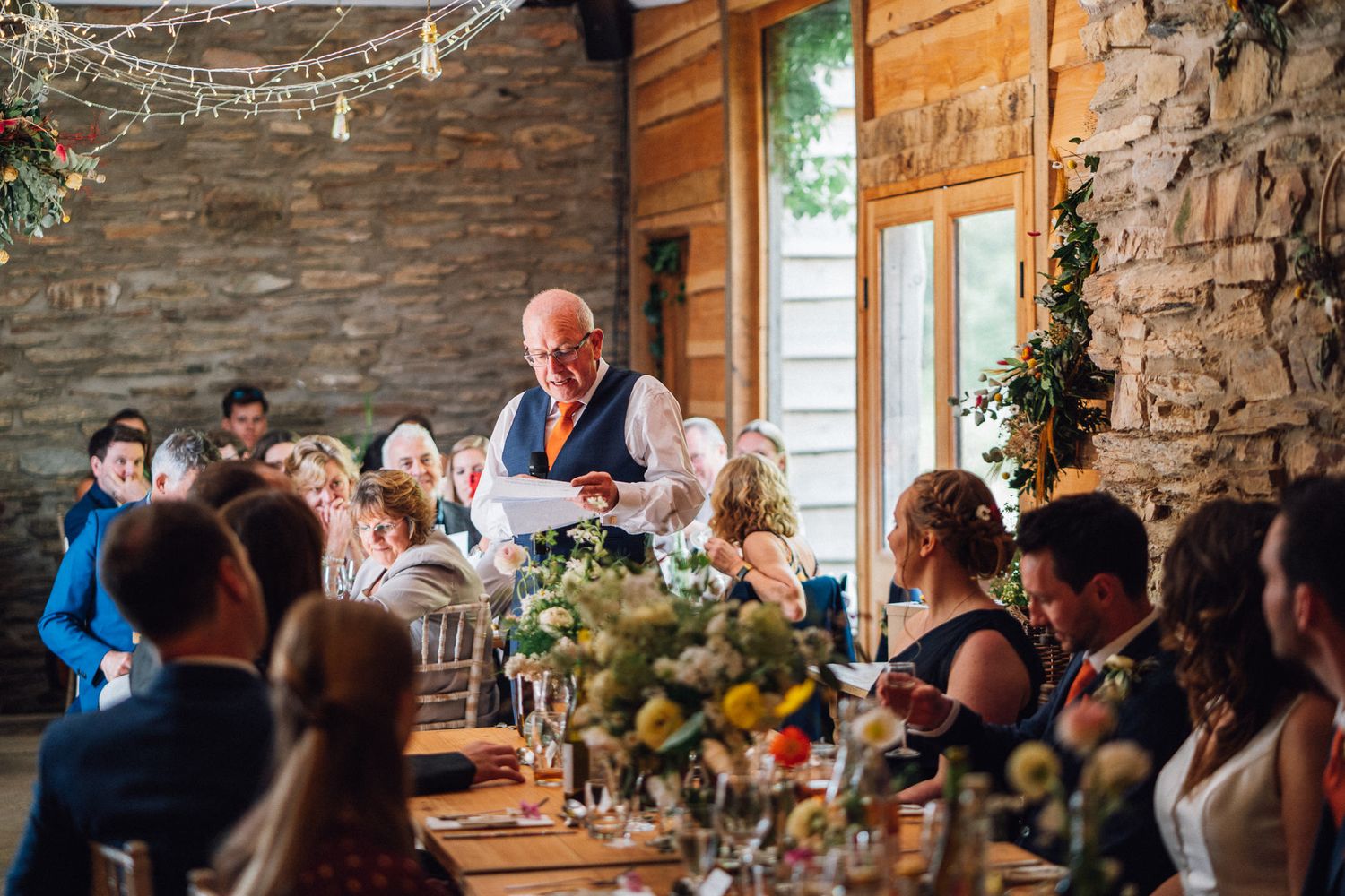 Wedding reception inside a rustic stone barn with exposed brick walls and natural lighting.