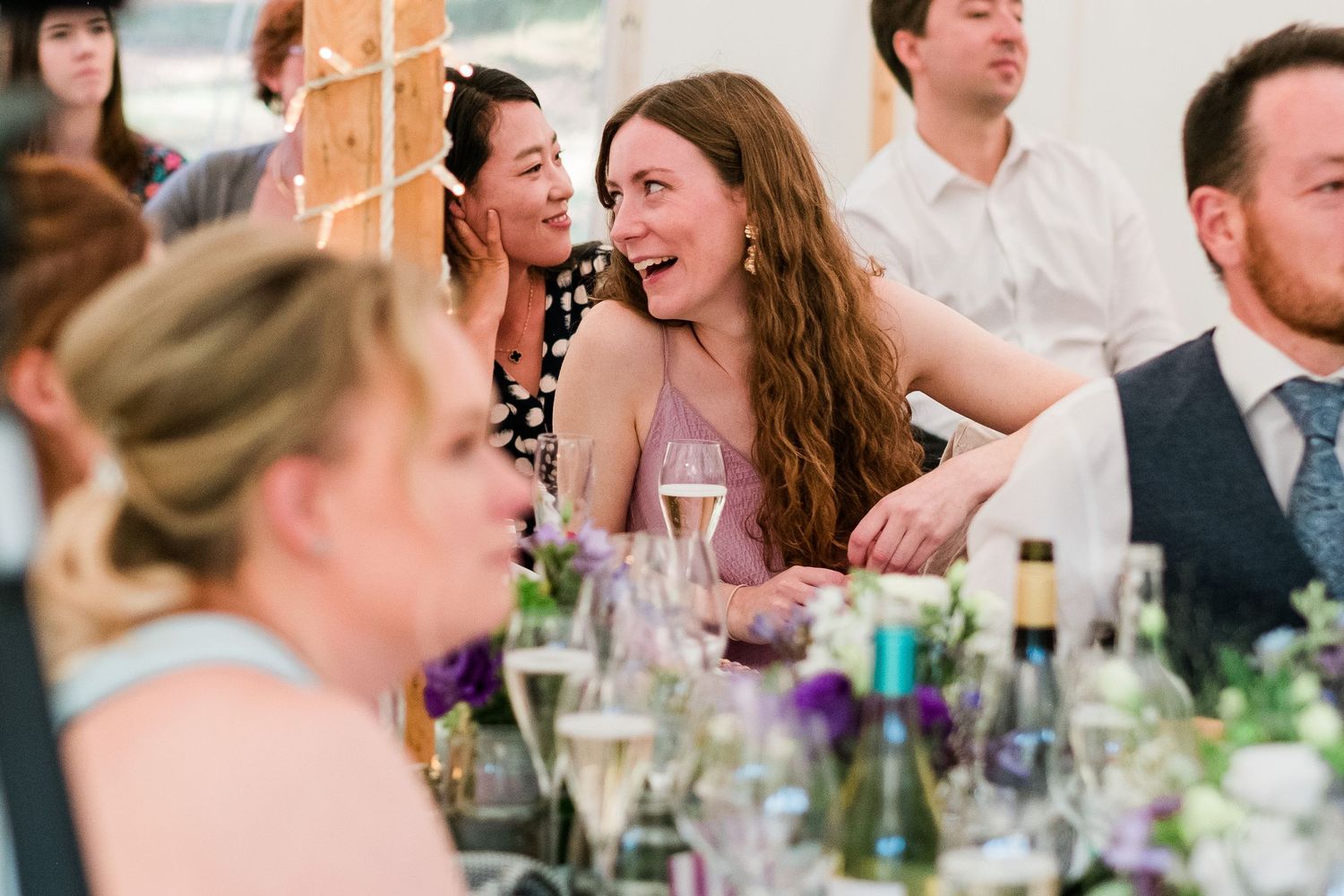Wedding reception guests engaged in lively conversation at decorated tables.