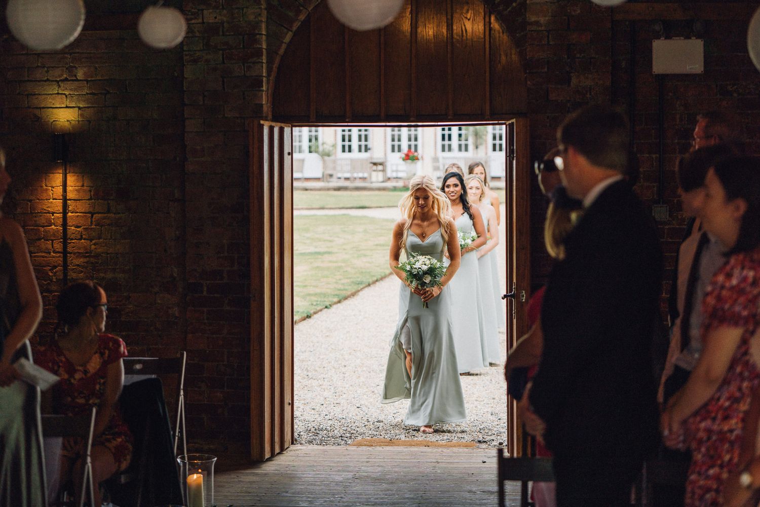 Wedding celebration in a dimly lit barn venue with rustic wooden beams and elegant decor.