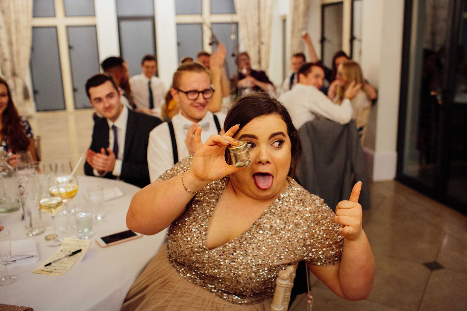 Wedding guests enjoying a celebratory dinner and toasting at an elegant indoor reception.