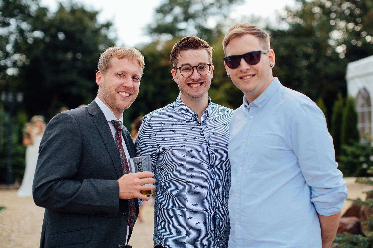 Guests in formal attire socializing at an outdoor summer wedding.