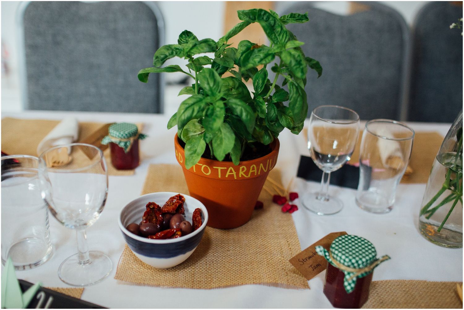 Wedding reception tables decorated with potted herbs and wine glasses.
