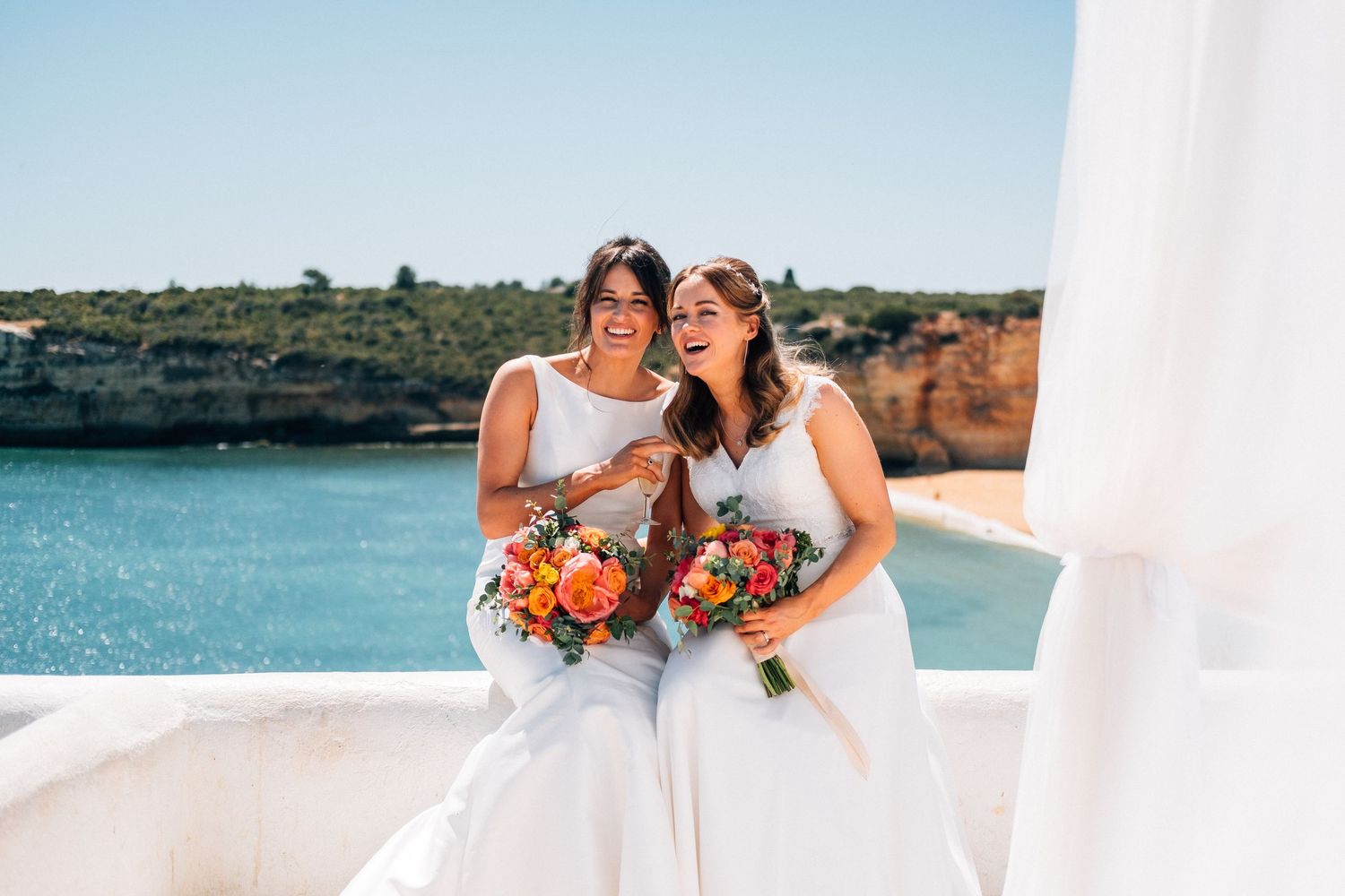 Wedding celebration by the ocean with white buildings and blue water in background.