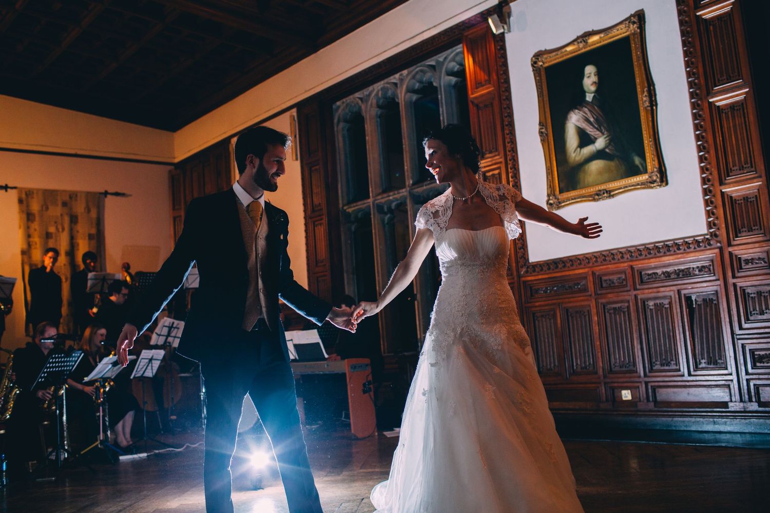 A couple dances in dramatic lighting at their wedding reception with band equipment visible.