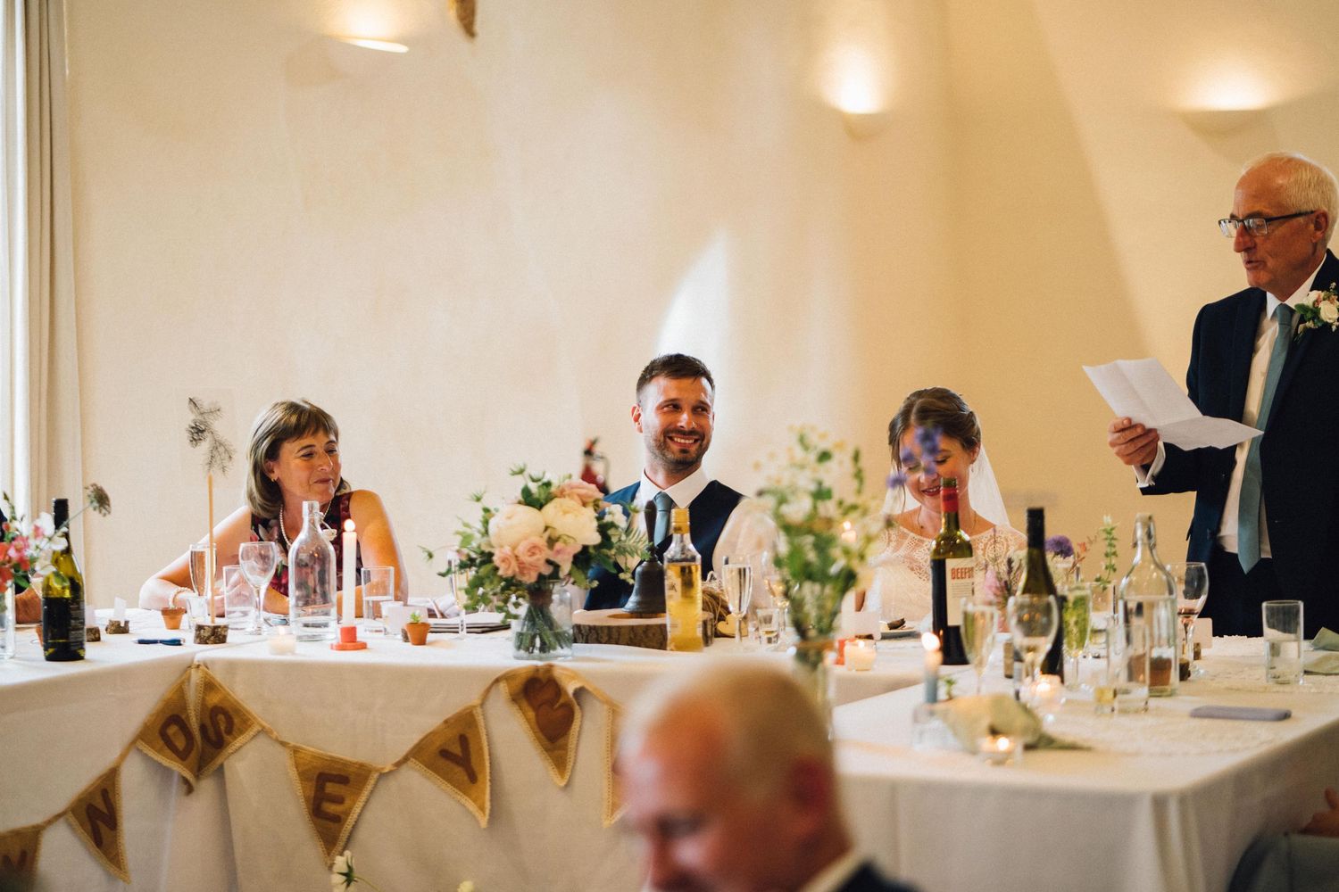 Panoramic view of wedding guests seated at long tables during reception dinner.