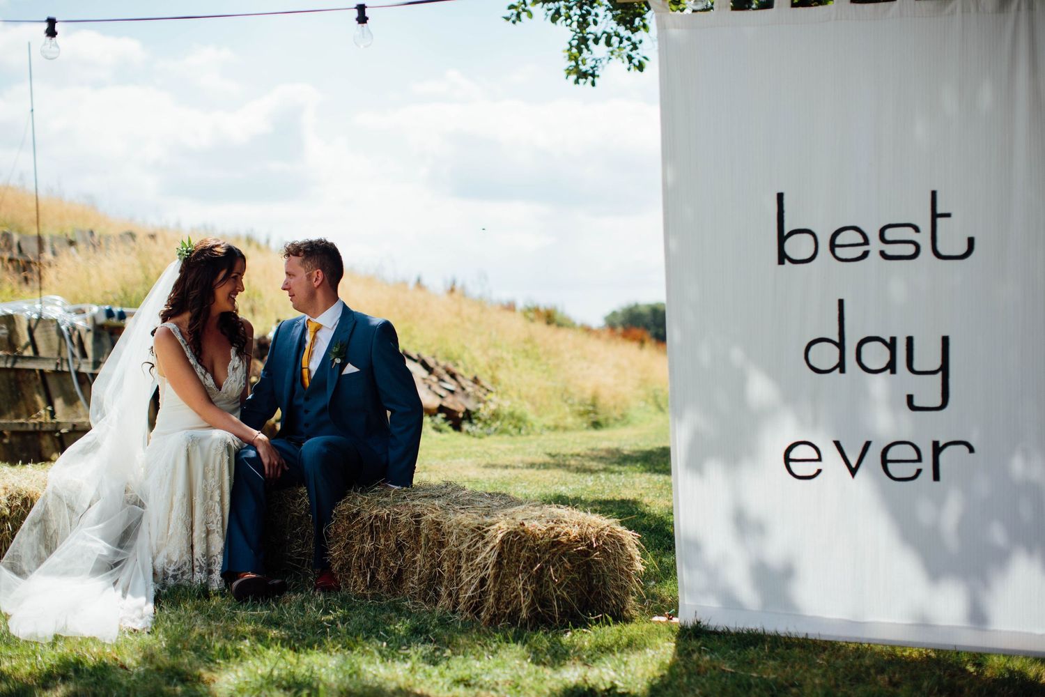 Wedding signage reading 'best day ever' displayed on white fabric panels in outdoor setting.