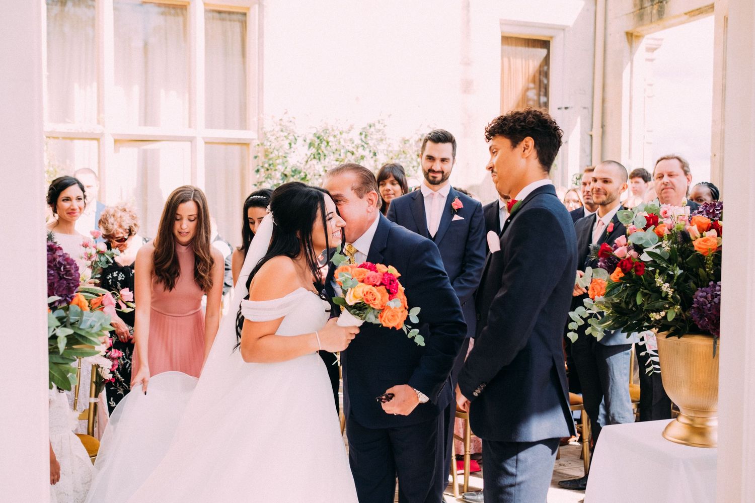 A wedding ceremony in progress with guests watching in a bright, window-lit room.