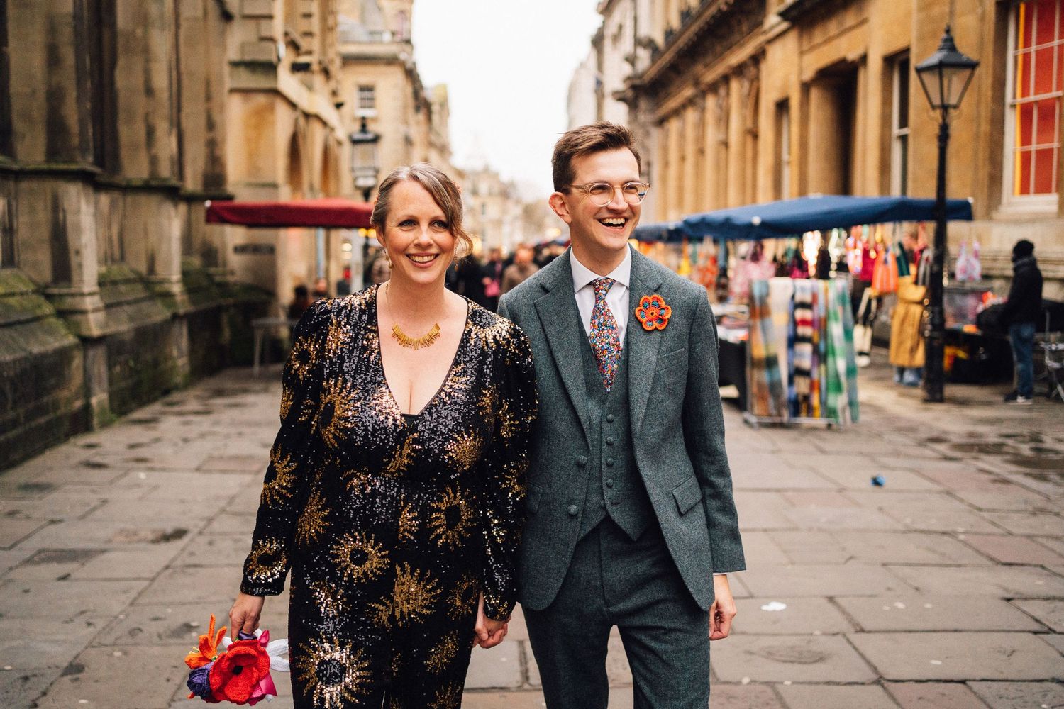 Couple strolls along historic stone street with market stalls in background.