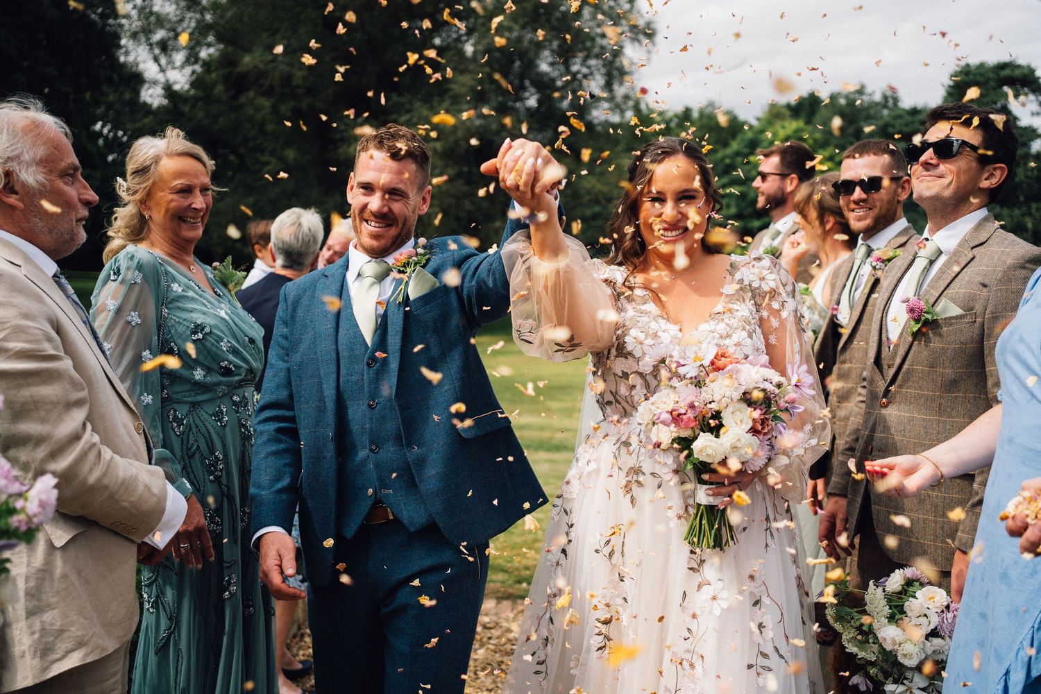 Wedding guests celebrate with confetti during an outdoor garden celebration.
