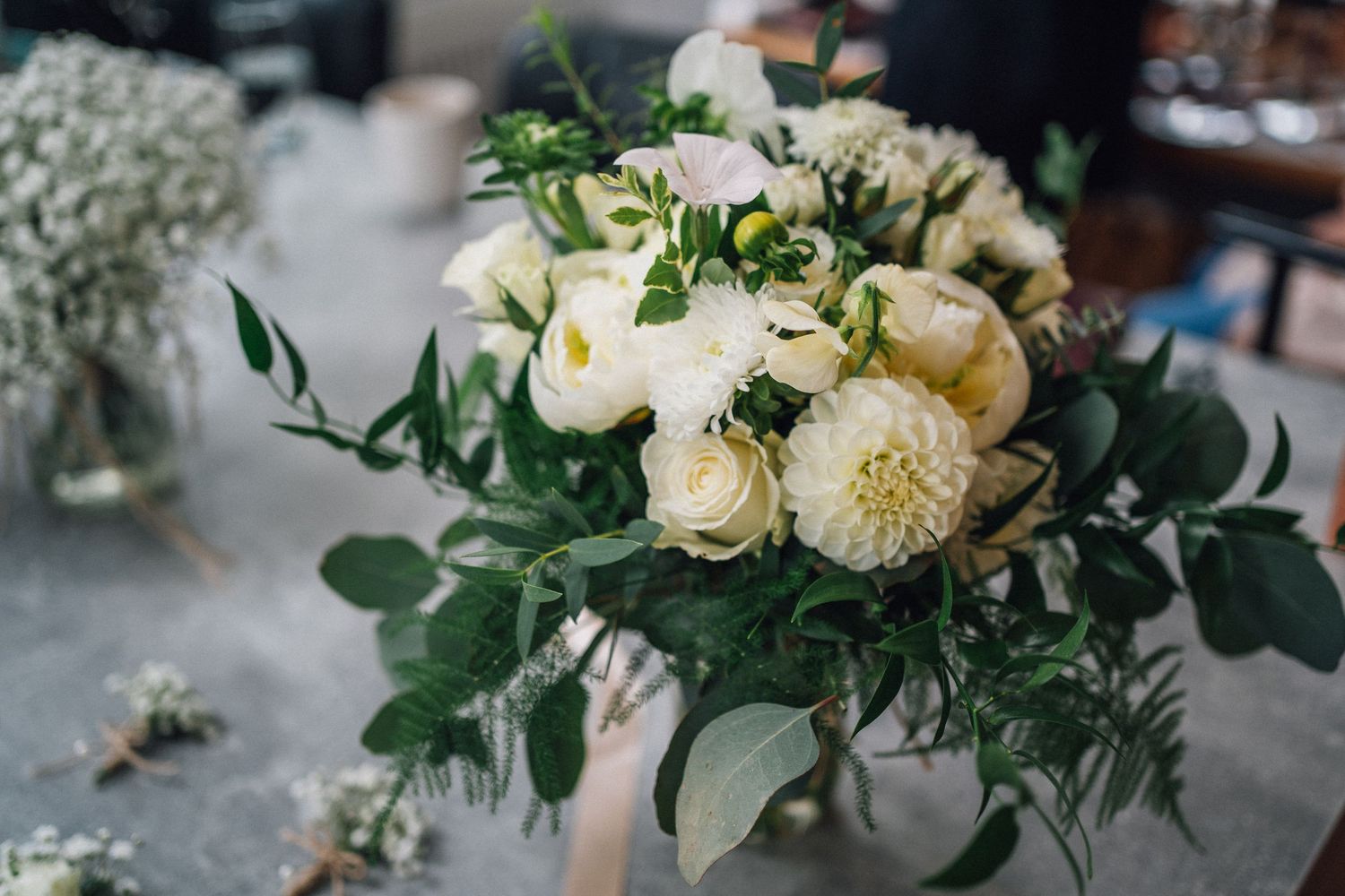 Elegant white floral arrangements with greenery decorate wedding tables.