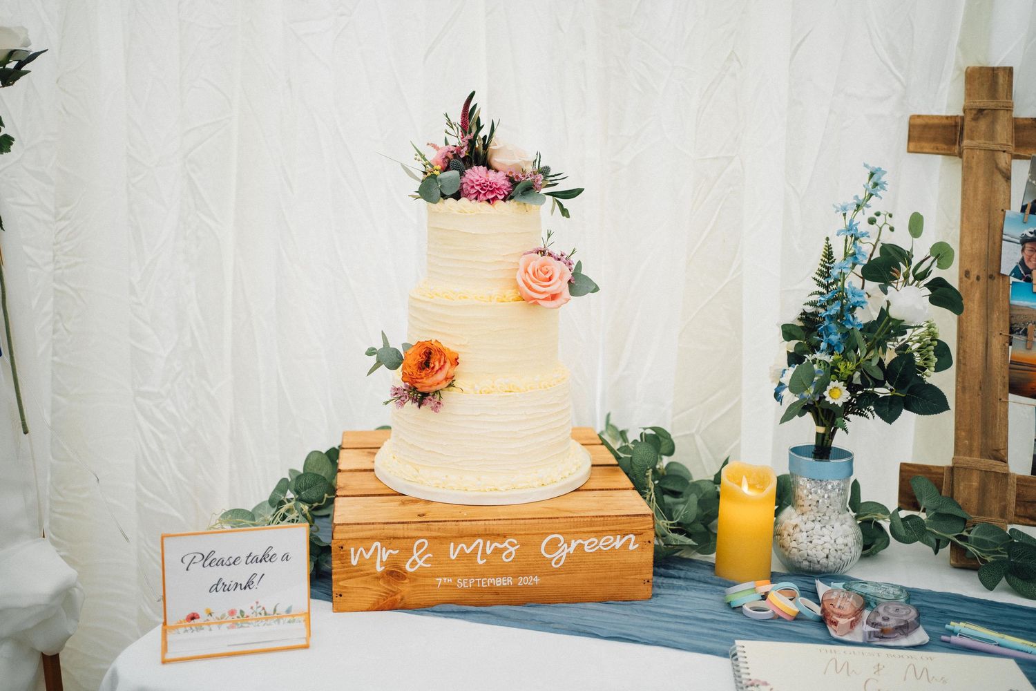 Wedding reception table decorated with wooden crosses, floral arrangements, and elegant place settings.