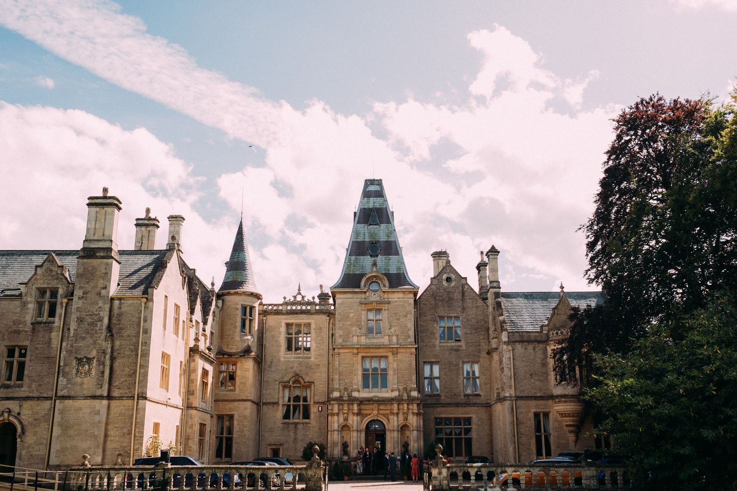 A stunning Gothic revival mansion with a distinctive spired tower photographed on a sunny day.
