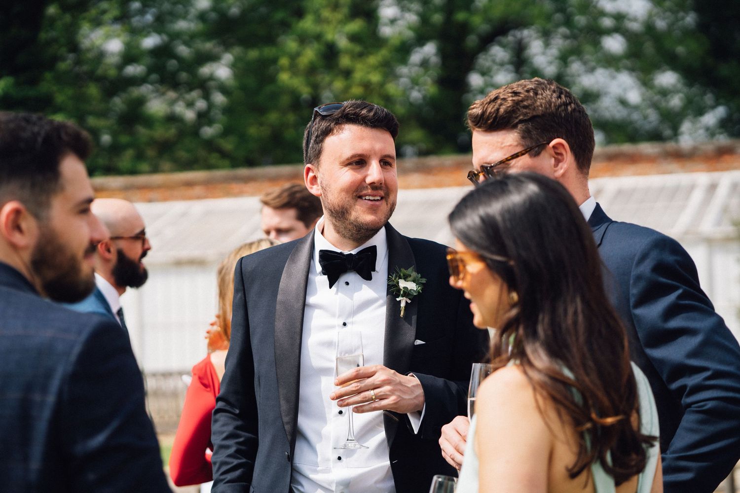Wedding party enjoying cocktail hour outdoors on a sunny day.