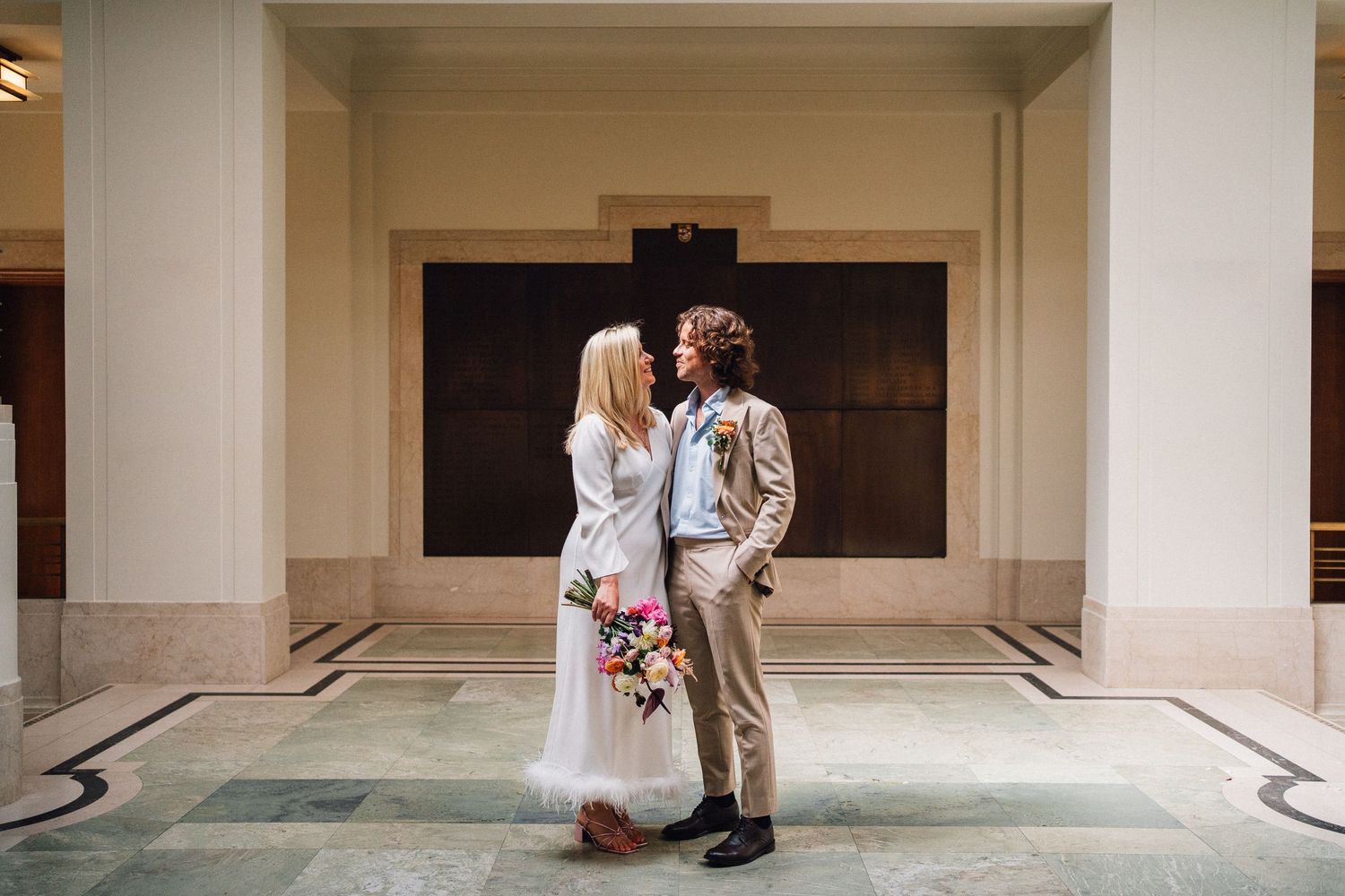 Couple sharing a romantic moment in a minimalist white hallway.