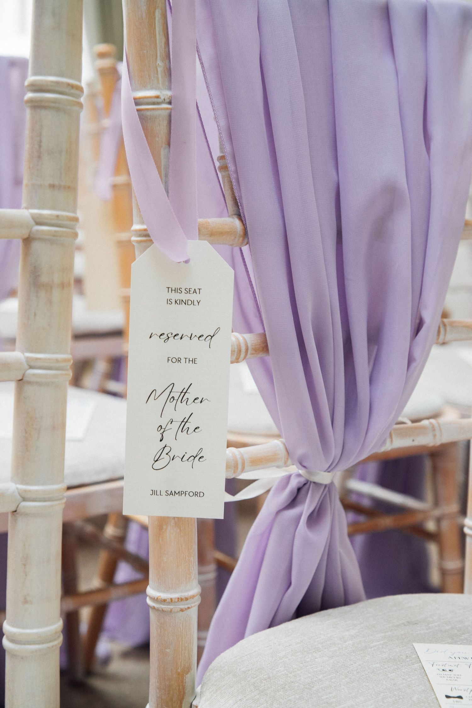 Light purple fabric drapes elegantly tied to white pillars with reserved seating signs at an elegant wedding venue.