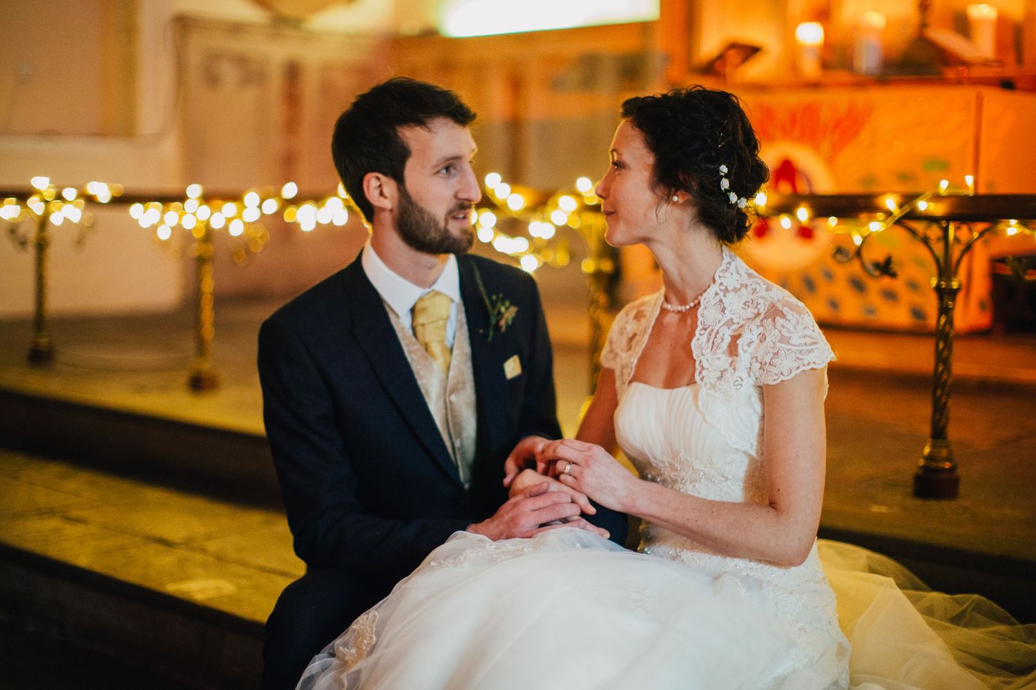 A tender moment shared during a wedding ceremony in a warmly lit church setting.