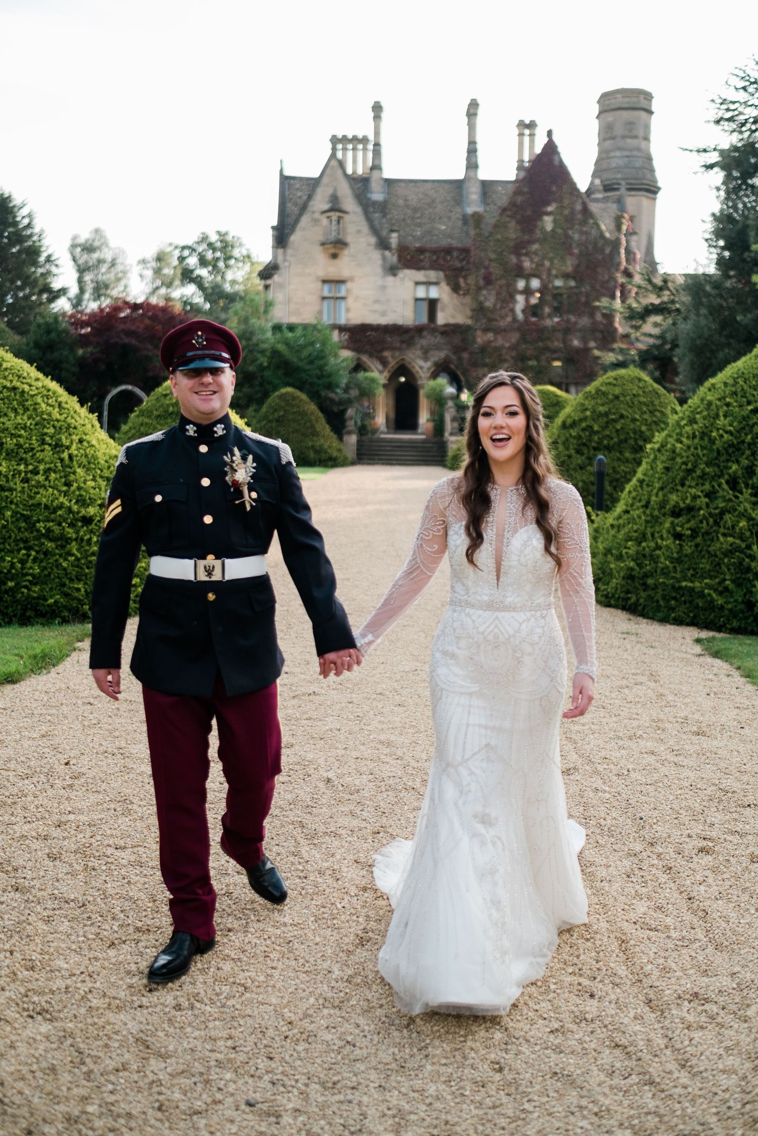 Playful wedding photos on a gravel path with historic buildings in background.