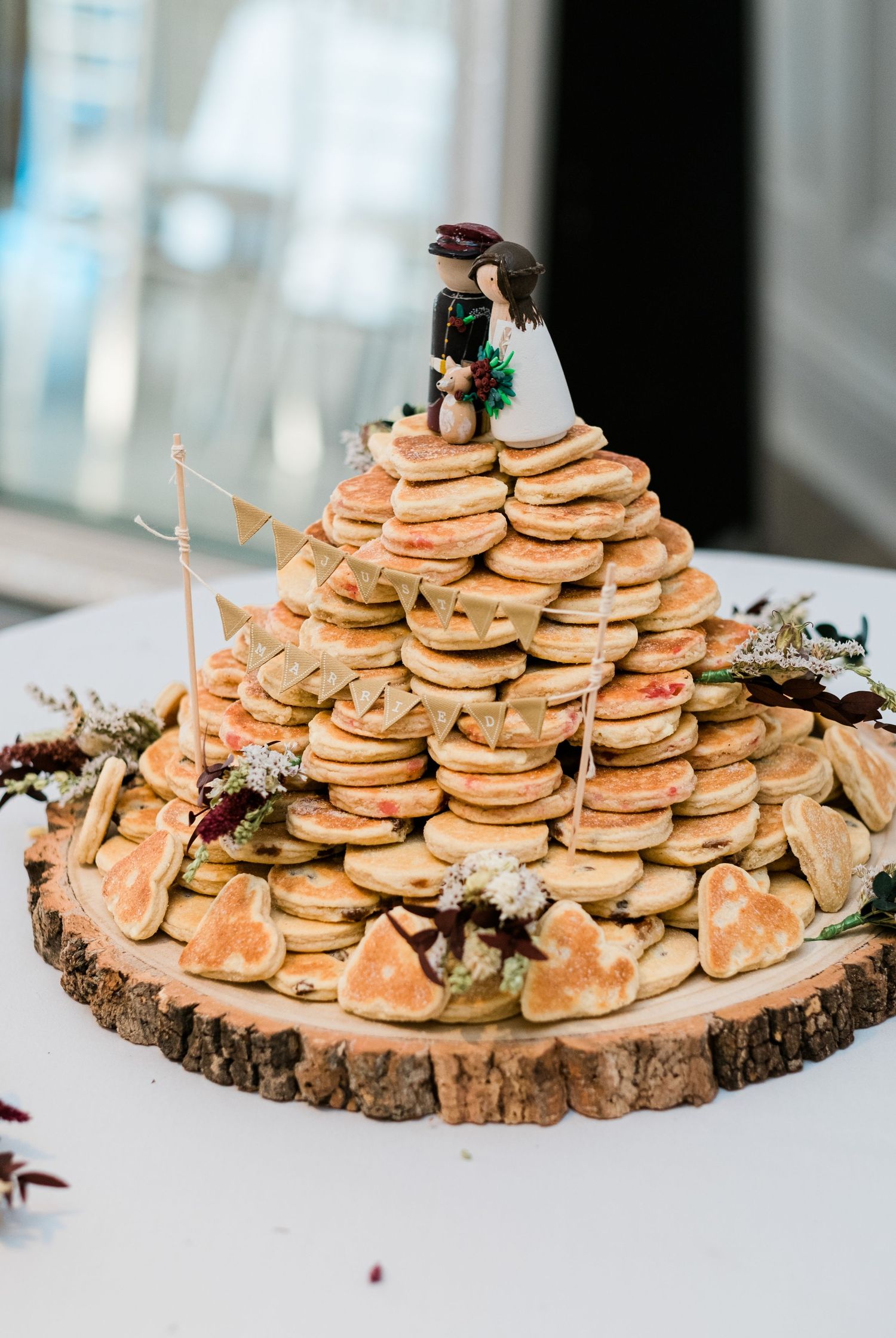 Tiered pancake display arranged on a rustic wood slice with natural decorative elements.
