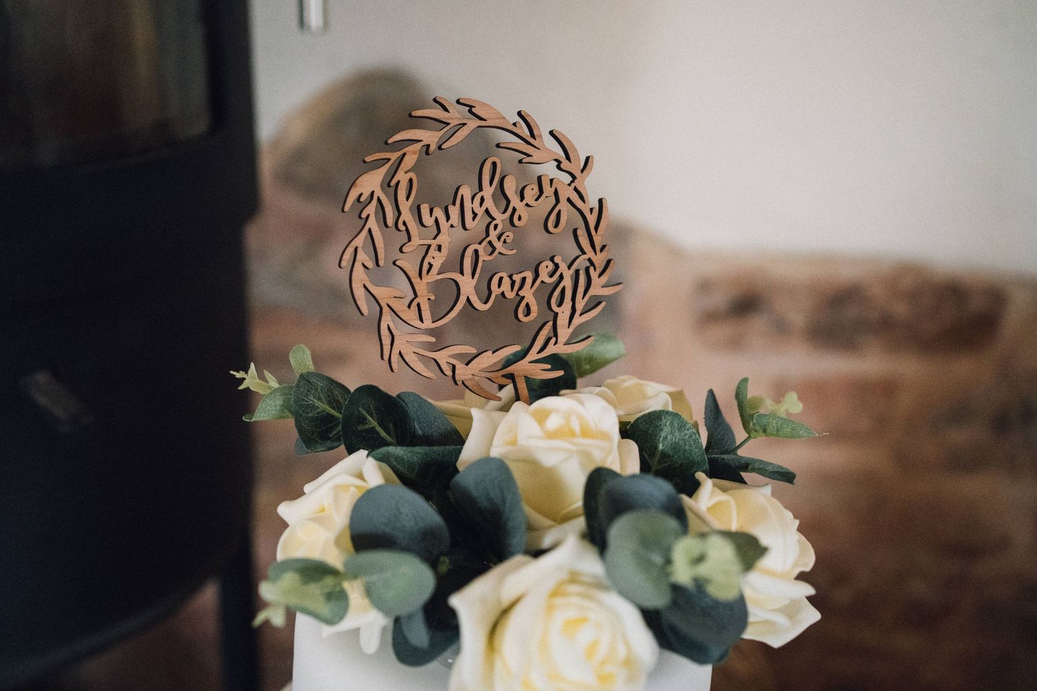 White wedding cake decorated with eucalyptus and roses on display.