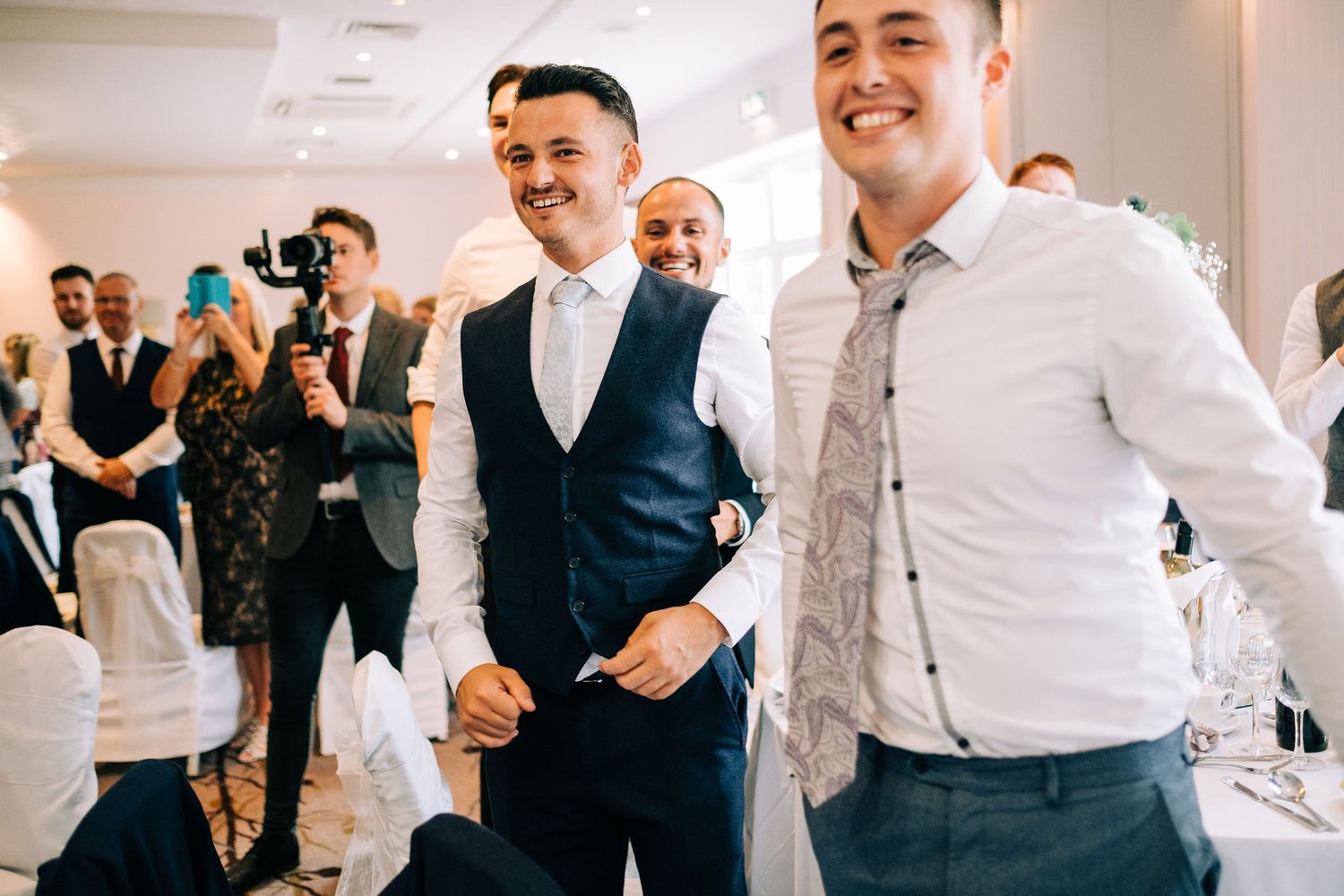 Lively wedding reception with guests dancing and celebrating in formal attire.
