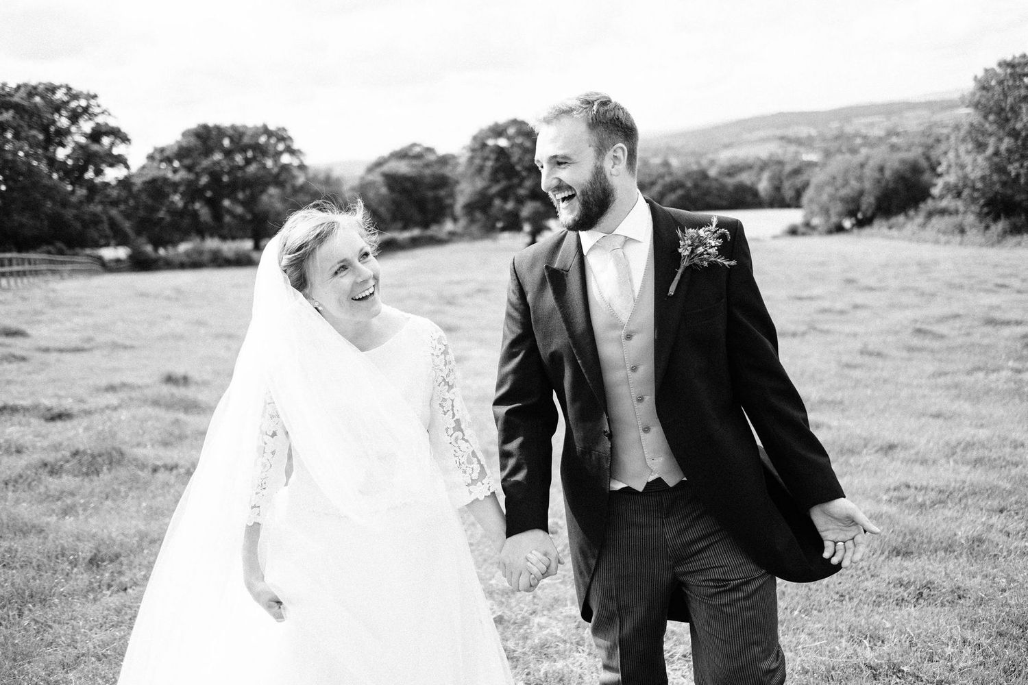 Couple sharing laughter while walking through a countryside meadow.