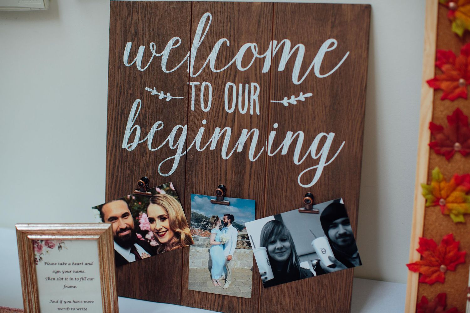 Rustic wooden welcome signs with handwritten text displayed on a wall with decorative autumn leaves.