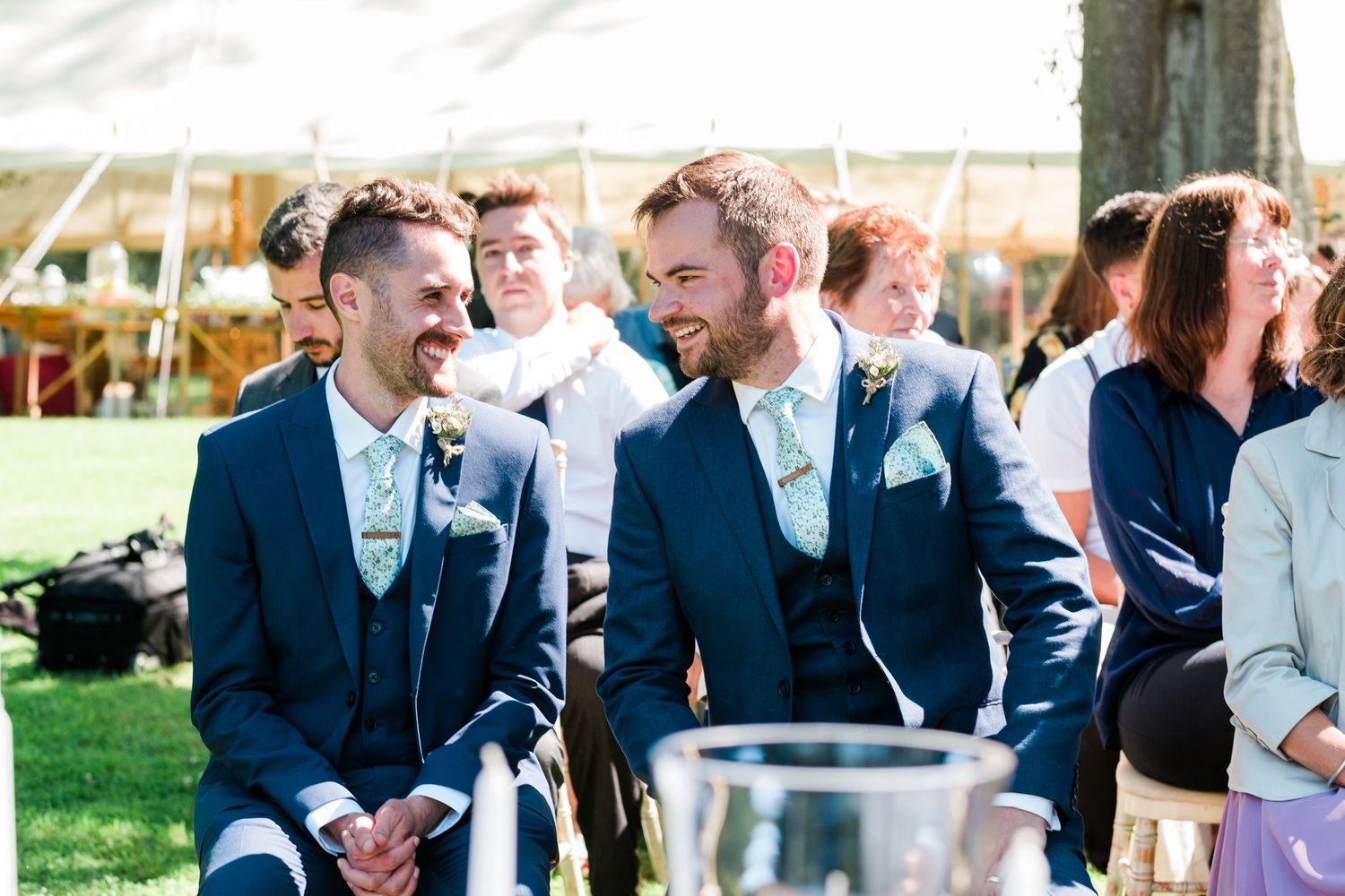 Wedding party gathers outdoors for celebration photos in formal attire.