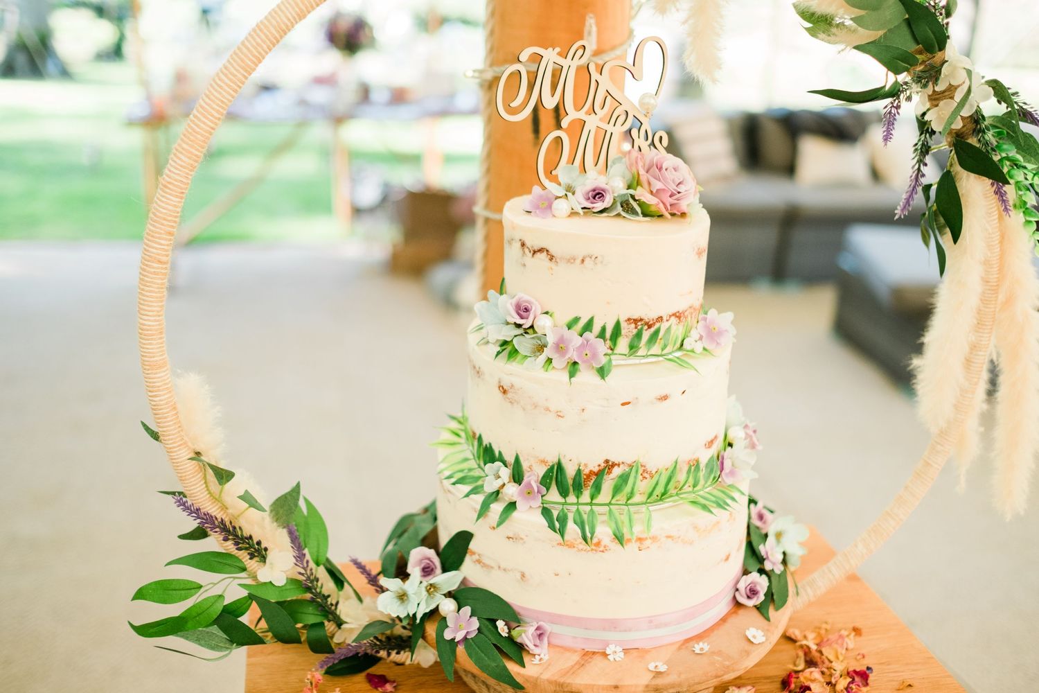 Close-up of a wedding cake with floral decorations and a gold cake topper.