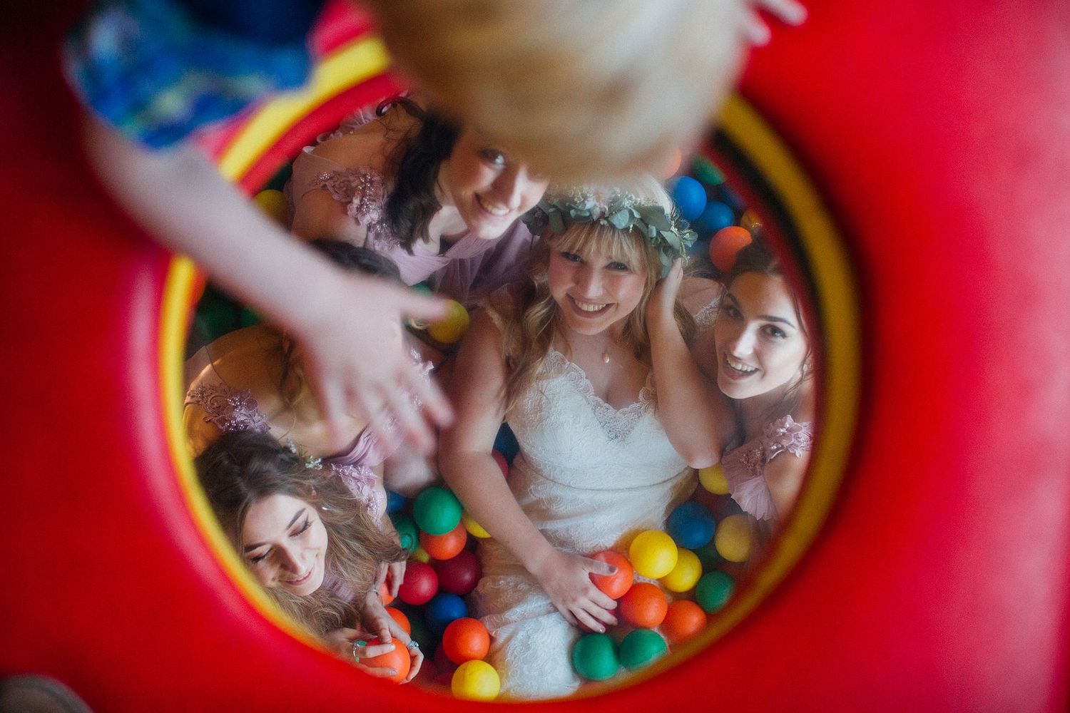 Children playing in a ball pit with colorful balls and inflatable surroundings.