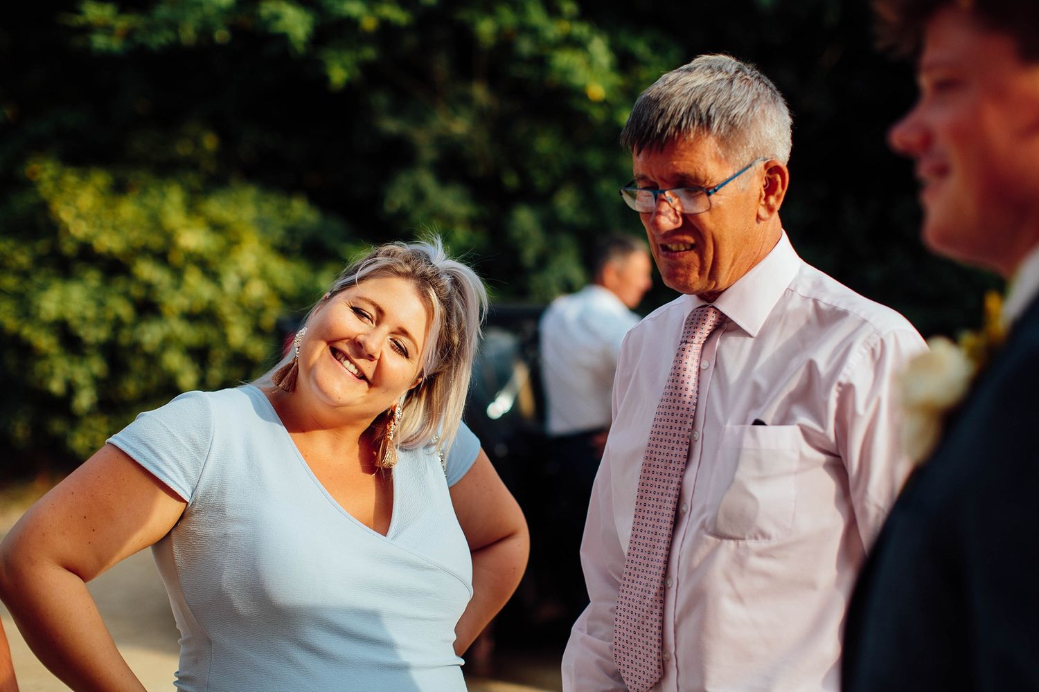 Wedding guests share a lighthearted moment during an outdoor summer celebration.