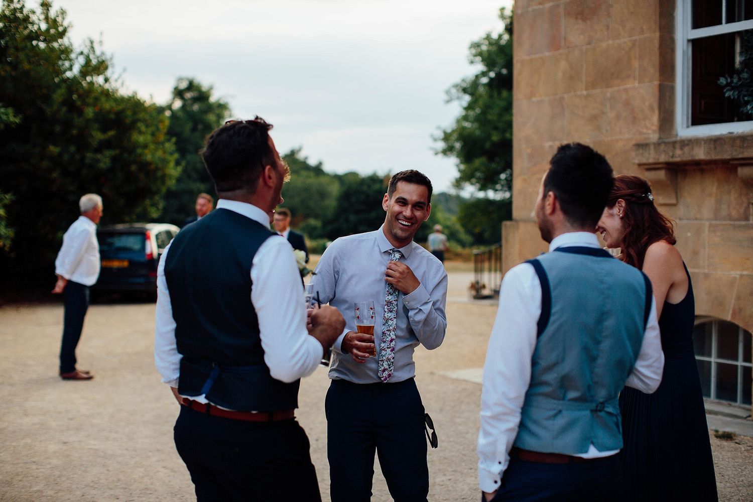 Small group in formal attire chatting and holding drinks outside.